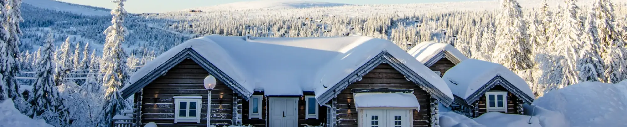 Entré till lyxig fjällstuga i Sälen med snötäckta tak och utsikt över fjällandskapet.