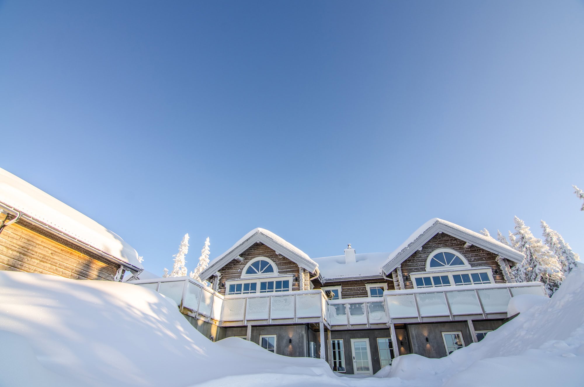 Modernt snöklätt fritidshus i naturskön miljö med panoramafönster och stor altan, perfekt för avkoppling och vinteraktiviteter i Sverige.