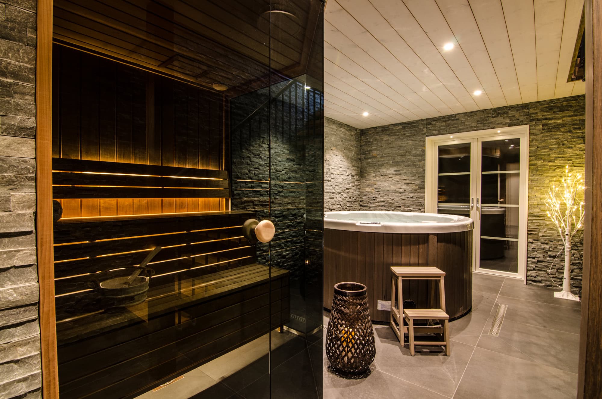 Ljust och inbjudande basturum med modern design, svart stenväggar och lyxigt badkar för avkopplande spa-upplevelser i hemmamiljön.