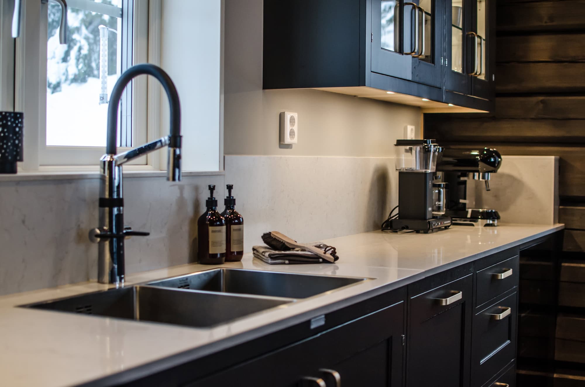 Snyggt och modernt kök med mörka skåp, ljus bänkskiva och stort fönster, perfekt för köksdesign och funktionalitet i hemmet.