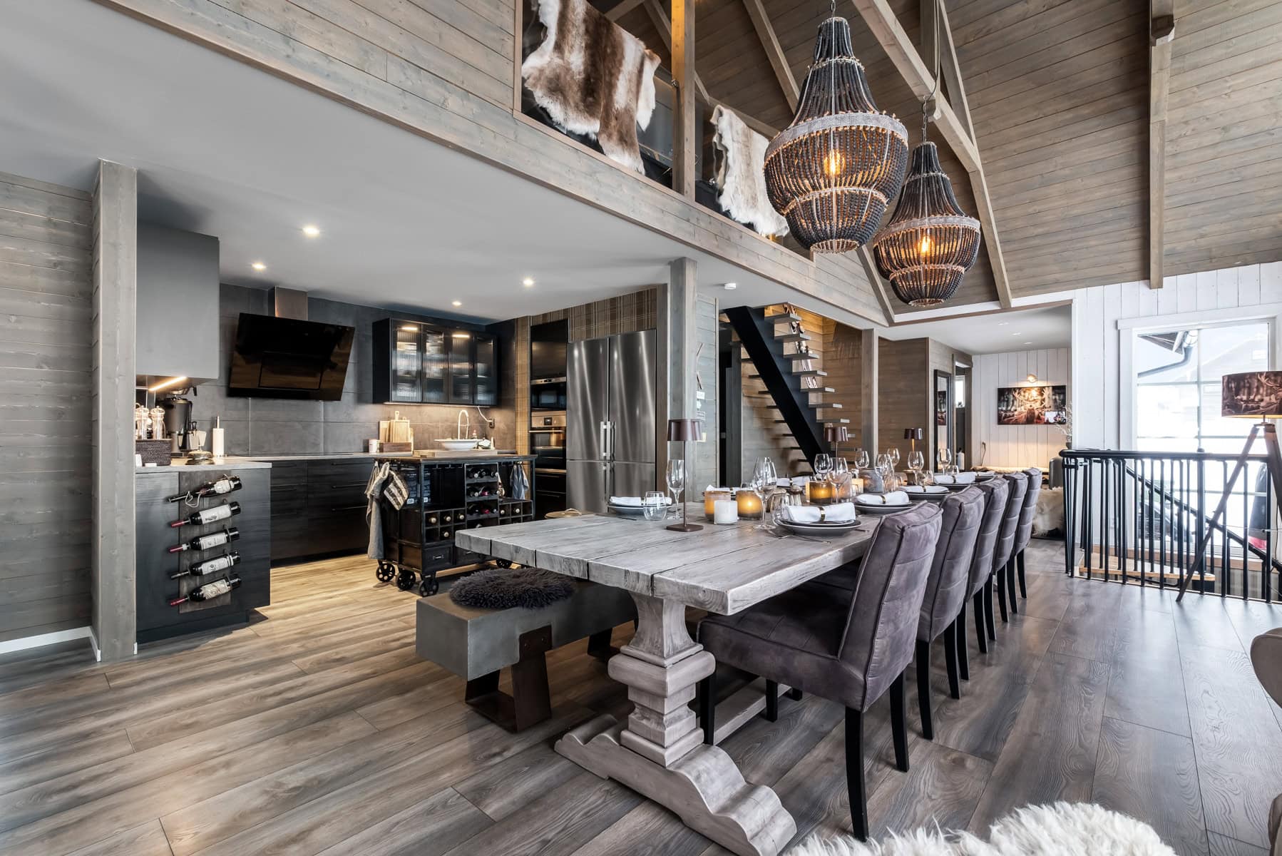 Rustik interiör i hem med trätak och modern kökslayout, samt dukat matbord för middagar i en avslappnad samtalsmiljö.