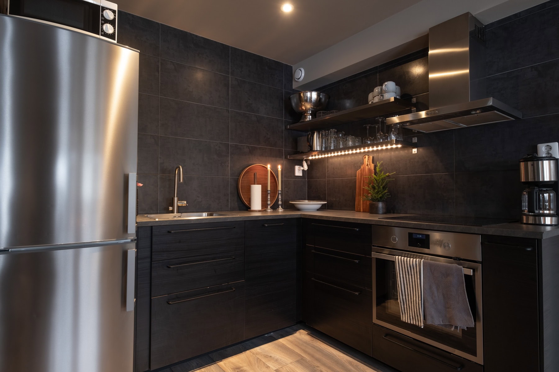 Elegant kök i modern design med svarta skåp och rostfria detaljer, perfekt för matlagning och trivsel.