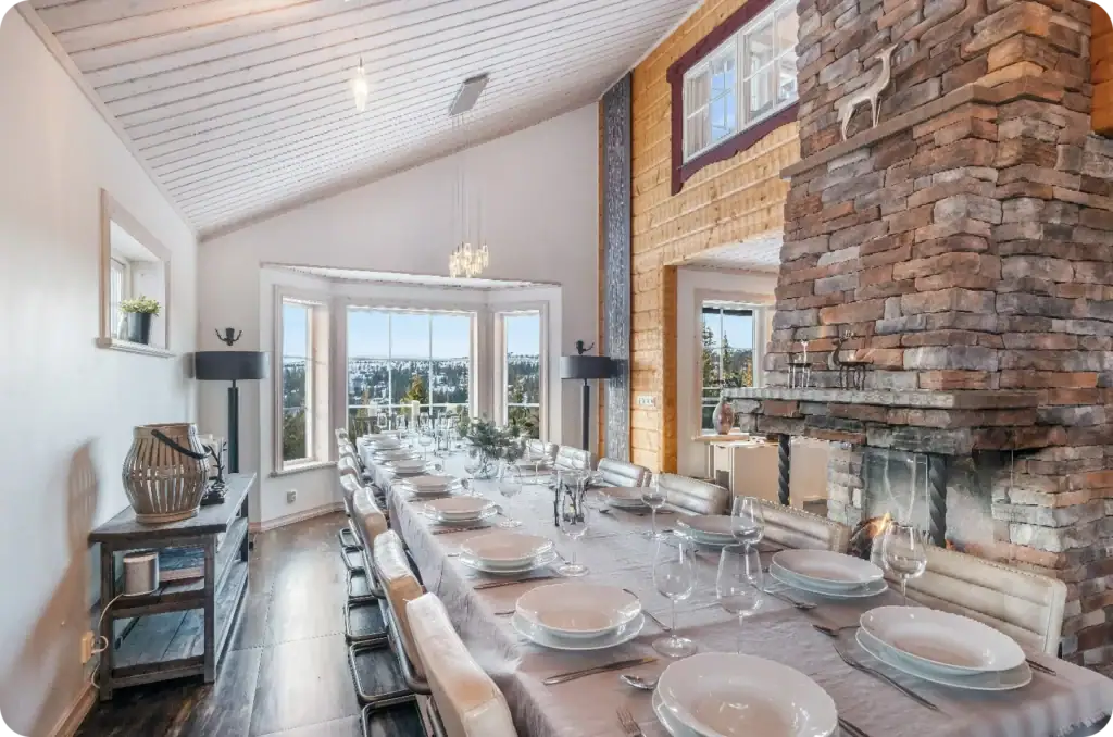 Lång matsal i fjällstuga med dukat bord och panoramautsikt över Sälenfjällen.