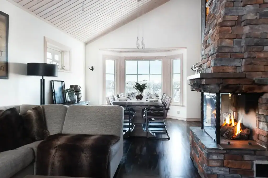 Vardagsrum i fjällstuga med soffa, stenvägg och öppen spis.