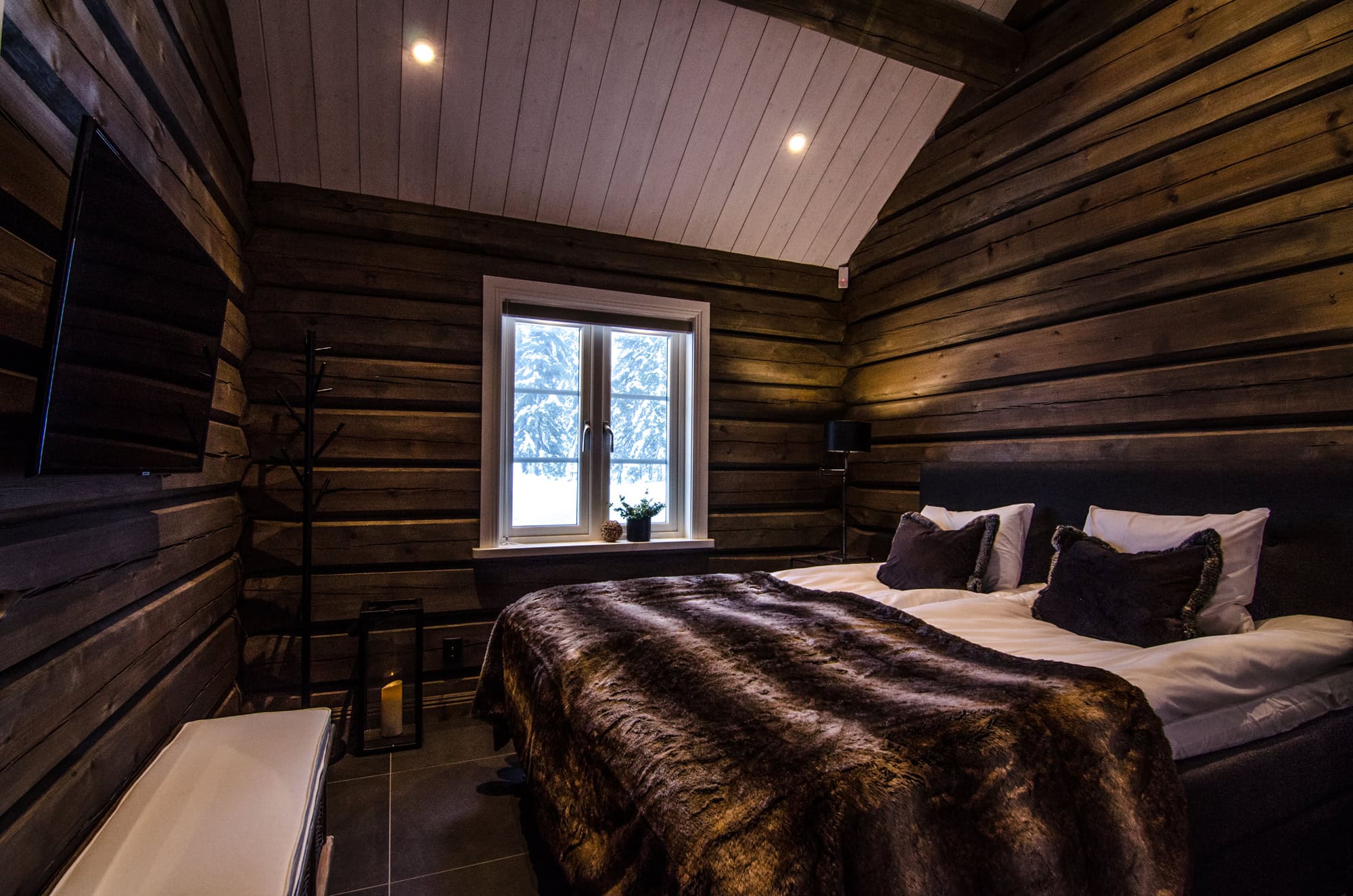 Rustikt sovrum i trähus med mysig atmosfär och vinterutsikt, perfekt för avkoppling och vila.
