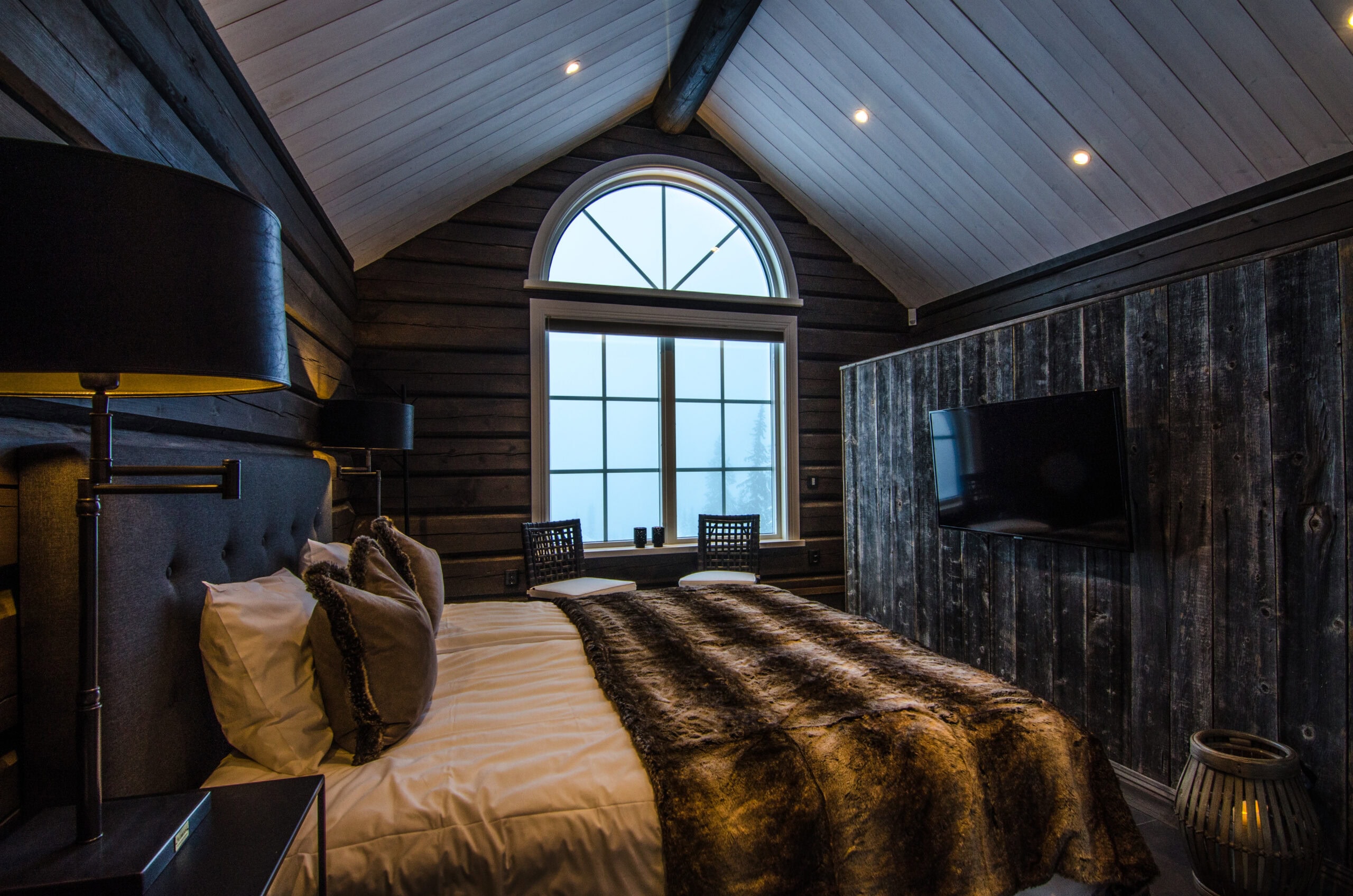 Elegant inredd hotellrum med træväggar och stort fönster som släpper in naturligt ljus, perfekt för avkoppling och sovkomfort. Modern design med mysiga detaljer och god sömn i fokus.