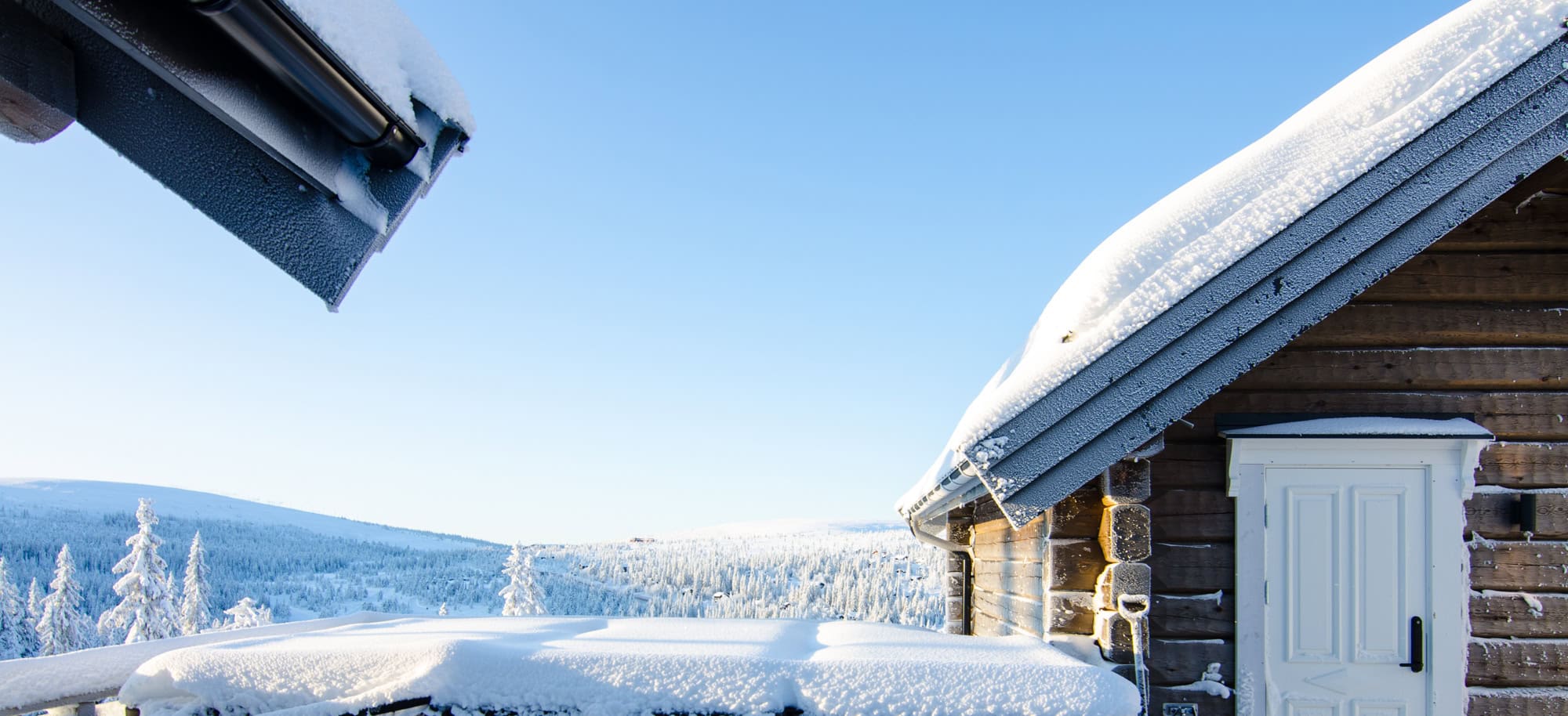 Snöbelagd tak på en trästuga i vinterlandskap, utomhusmiljö.