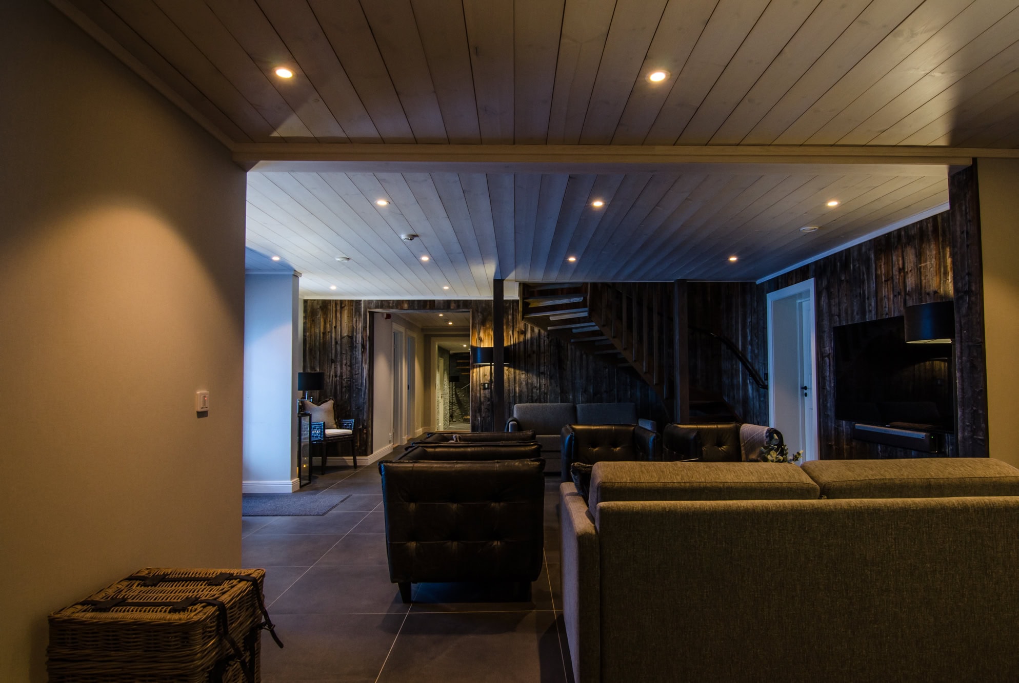 Mysig lounge med modern inredning, bekväma soffor, träväggar och TV, perfekt för avkoppling och socialt umgänge i en inbjudande miljö.