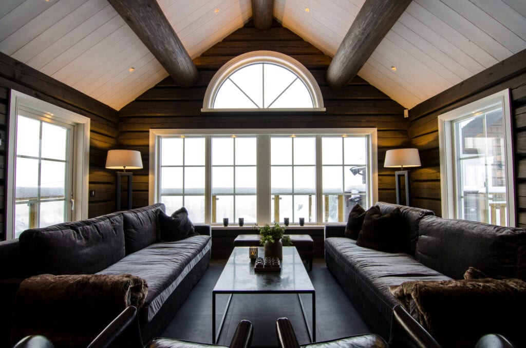 Elegant rustiek huisinterieur met grote ramen, houten muren en comfortabele banken, perfect om te ontspannen in een schilderachtige omgeving, ideaal om te loungen en te ontspannen in een op de natuur georiënteerd leven.