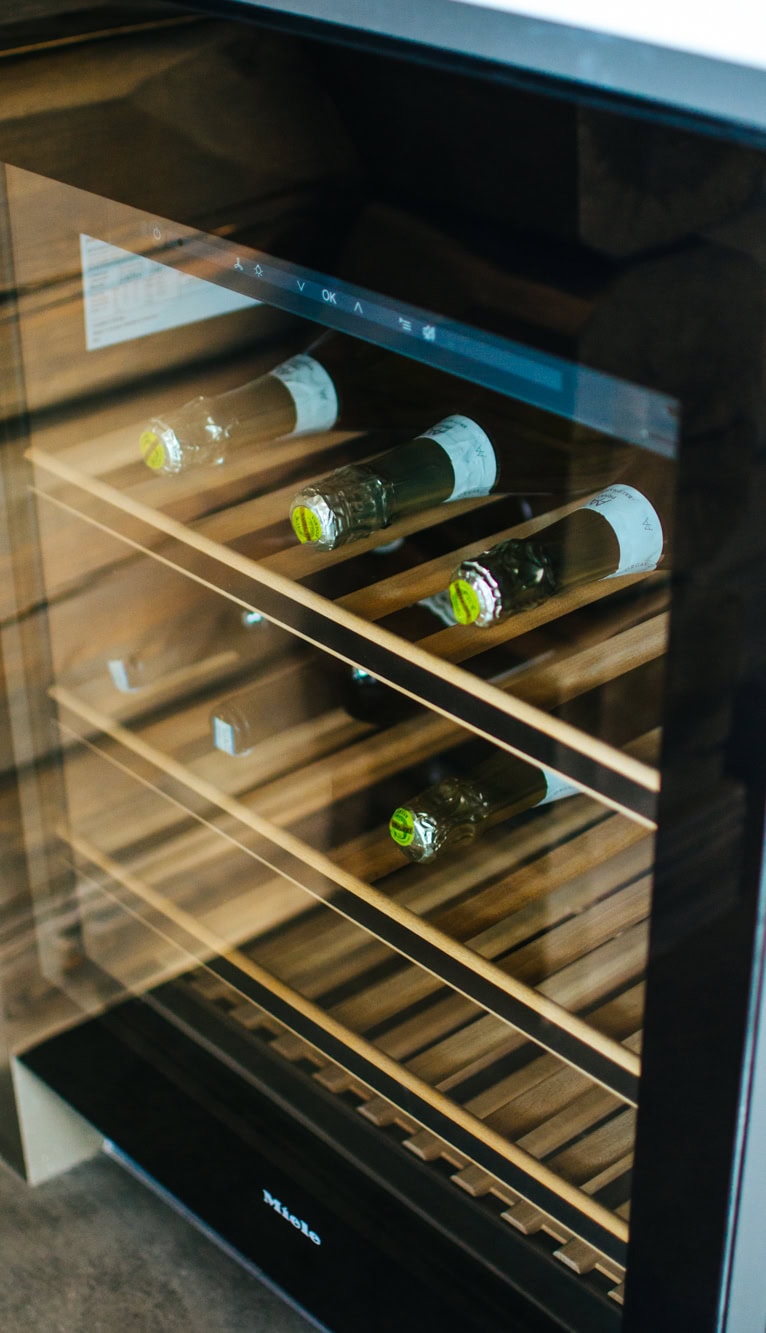 Liten vinkyl med glasdörr och träreglar för vinflaskor, perfekt för vinälskare och hem med elegant inredning.