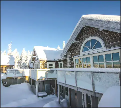 Lyxig fjällstuga i Sälen med snötäckta tak och solig vinterdag.