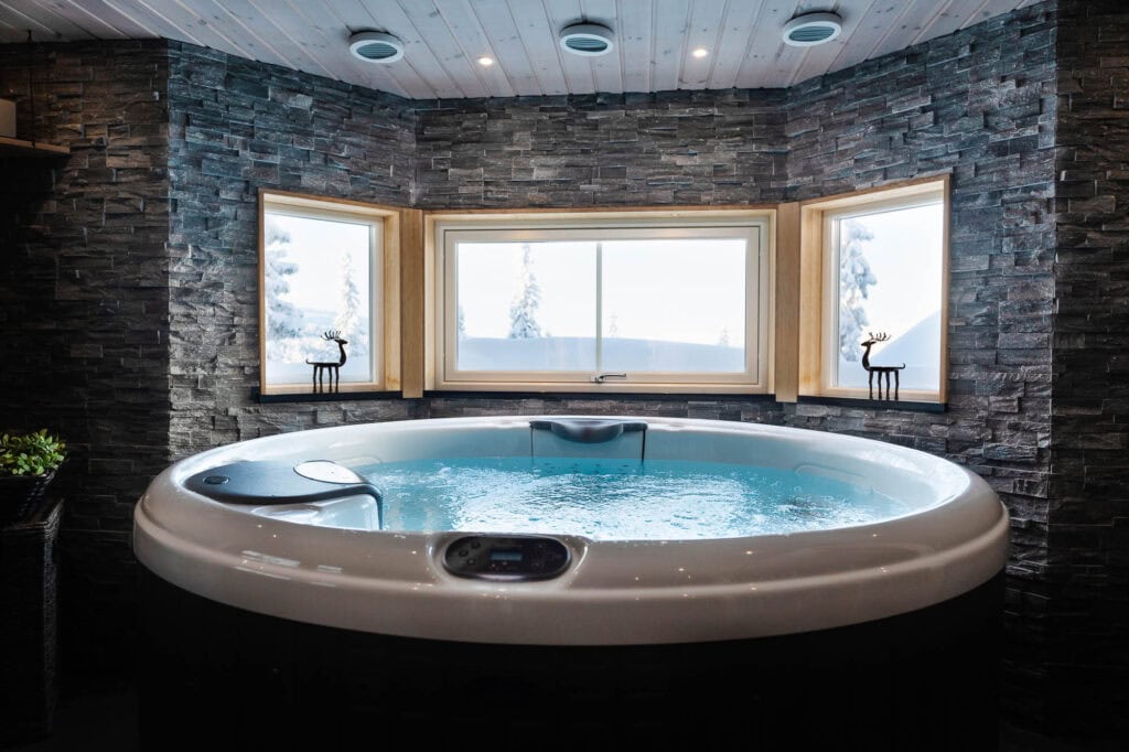 Inomhusjacuzzi med panoramafönster och utsikt över snöklädda fjäll i Sälen