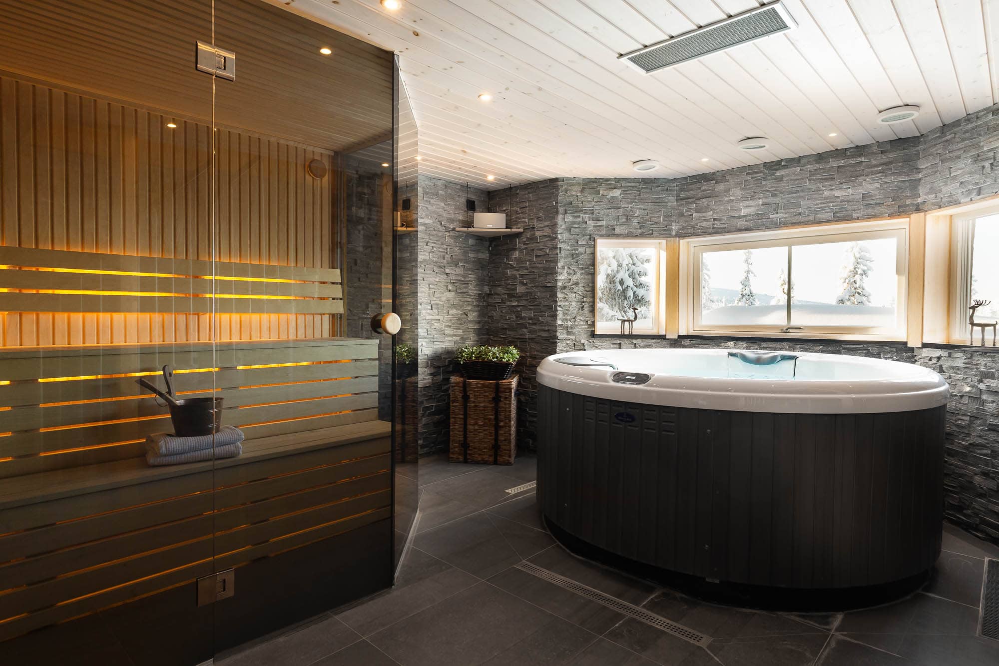 Spa de luxe avec sauna et jacuzzi dans un chalet de montagne avec vue sur les arbres enneigés