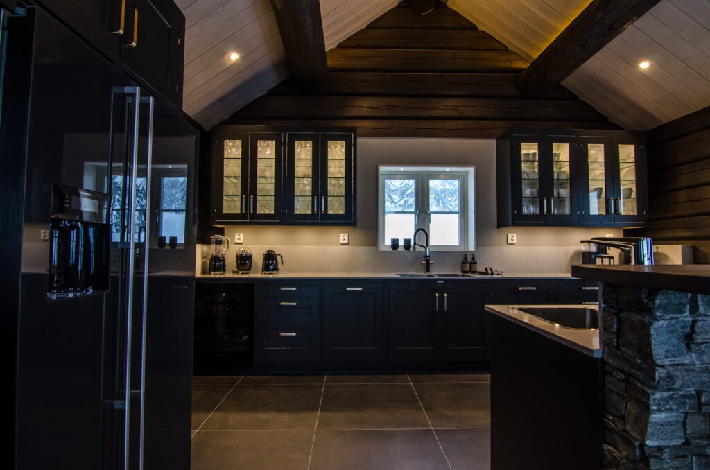 Exklusivt kök i fjällstuga i Sälen med mörka skåp och stenvägg
