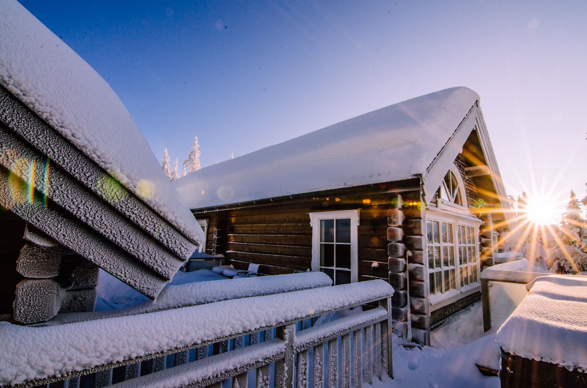 Snöklädd fjällstuga i Sälen med soluppgång som lyser över taken