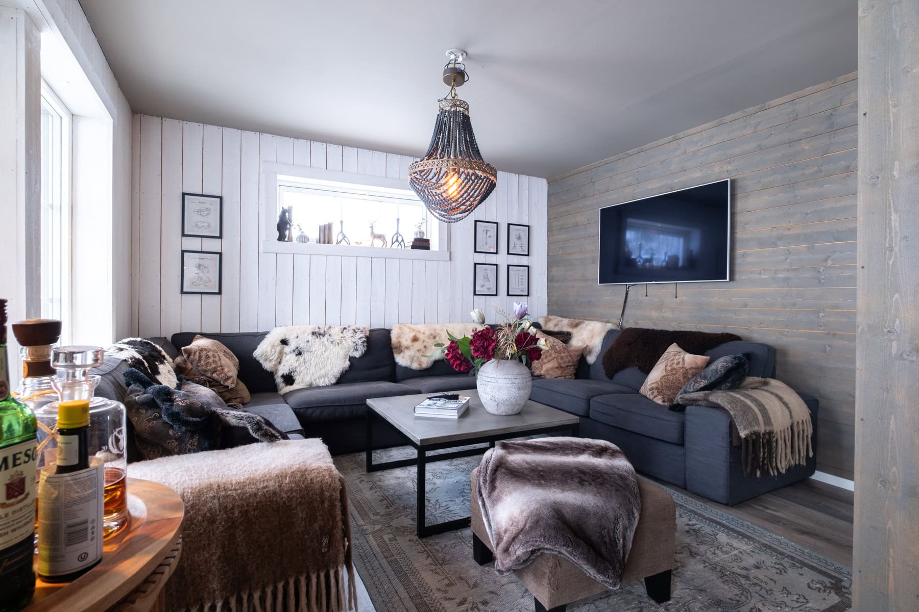 Mysigt vardagsrum i Olarslodgen med stor soffa, plädar och TV