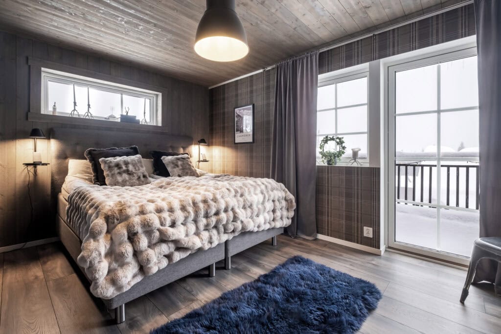 Sovrum i Olarslodgen med stor dubbelsäng, lyxiga fällar och utsikt över snötäckta fjäll