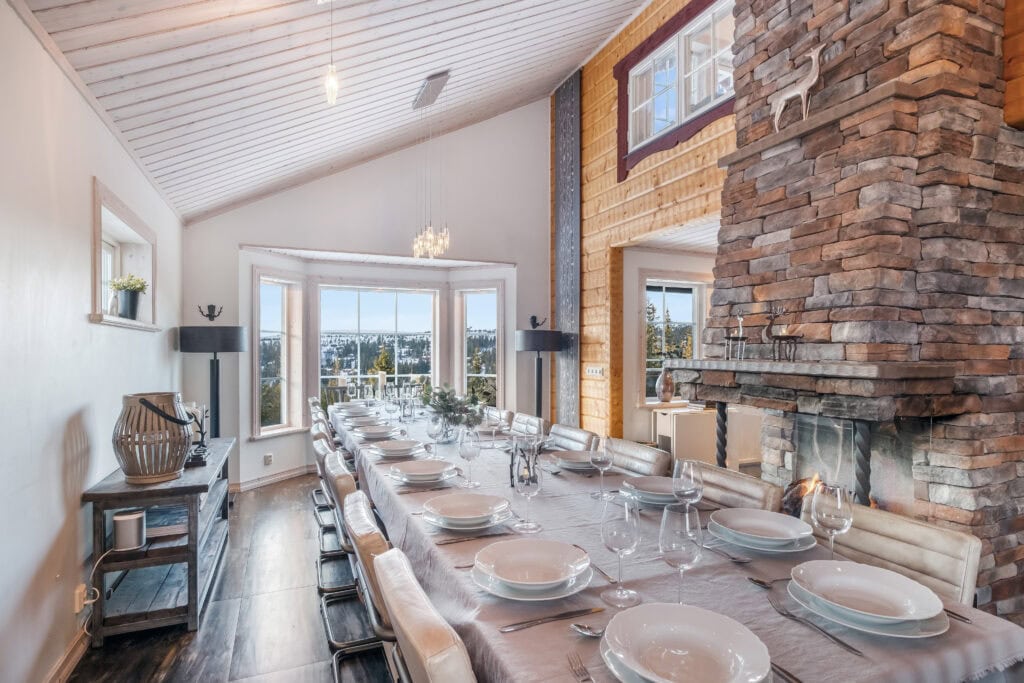 Stilfullt dukat långbord framför öppen spis med utsikt över fjällen i Sälen