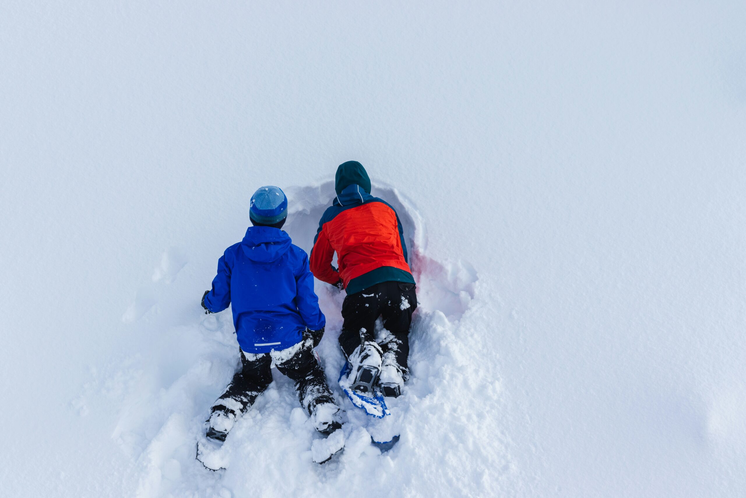 Två barn bygger en snögrotta i djup snö