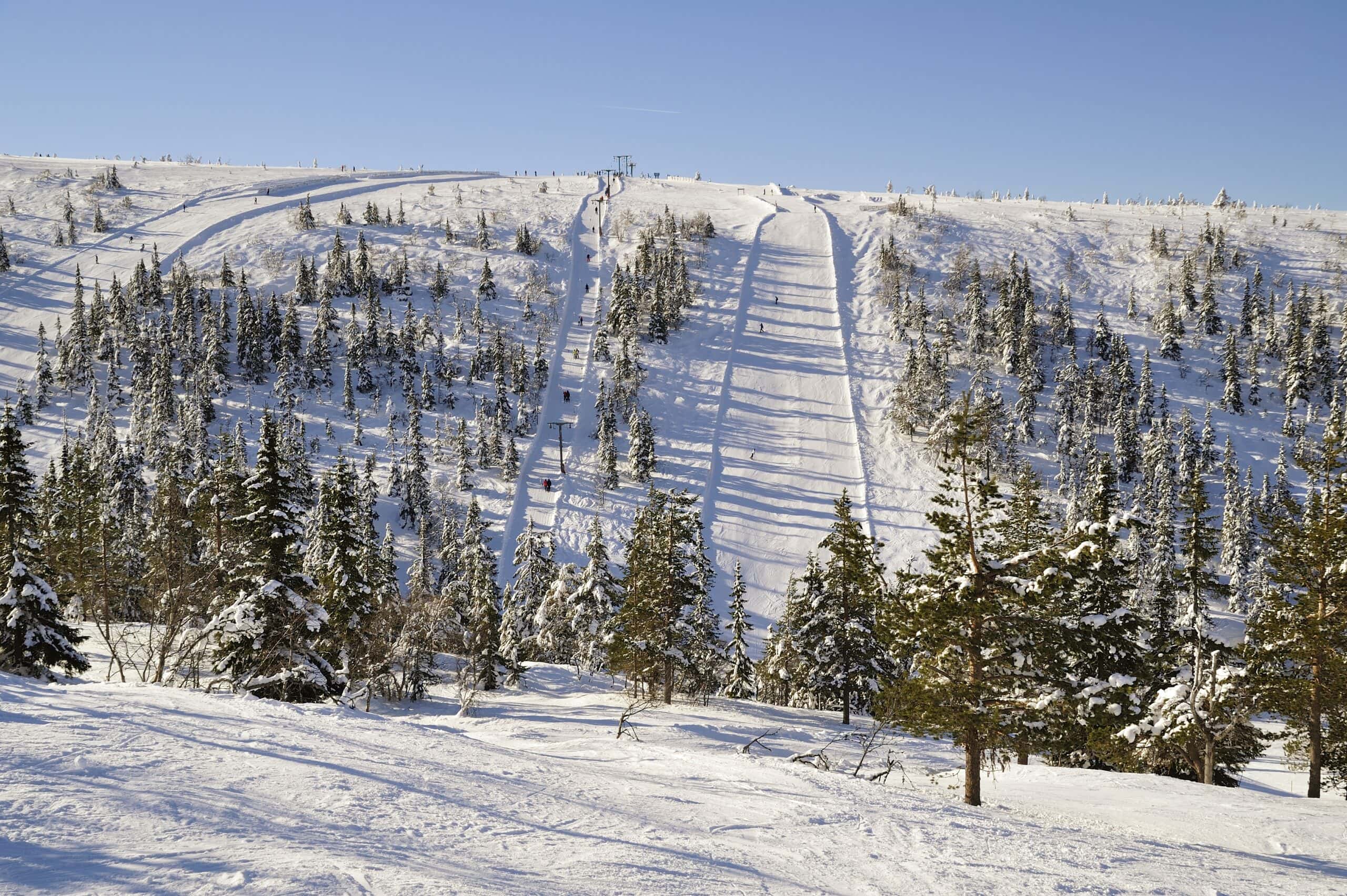 Soliga skidbackar med liftar och skidåkare i Sälen