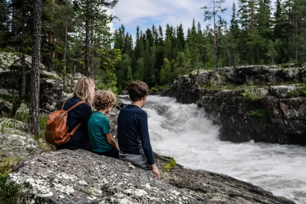 Familj som sitter på klippor vid fors i Sälenfjällen en sommardag