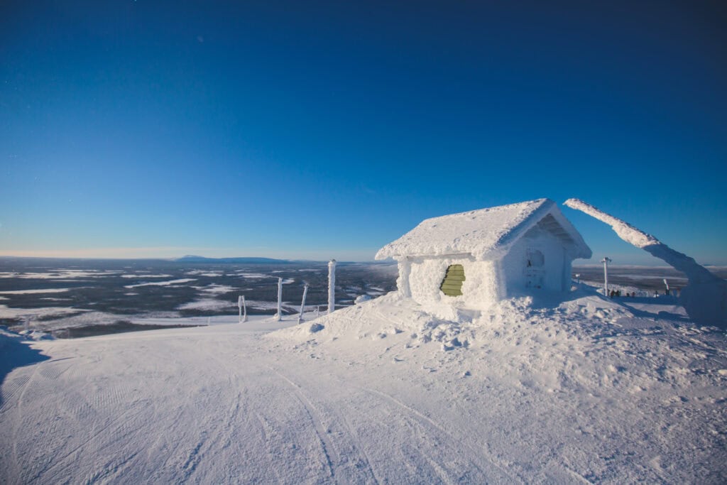 Snötäckt fjällstuga på fjälltoppen i Sälen med milsvid utsikt över vinterlandskapet