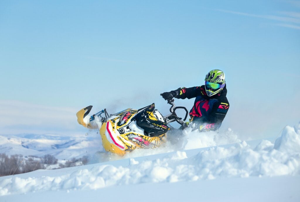 Skoteråkare i full fart på gul snöskoter i pudersnö