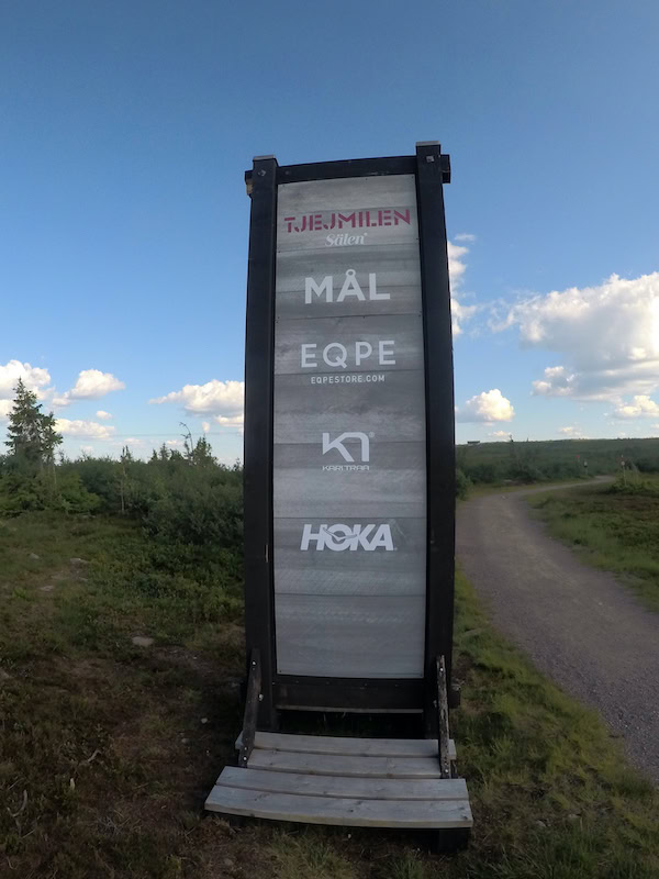 Målgång för Tjejmilen i Sälen med sponsorloggor på träskylt