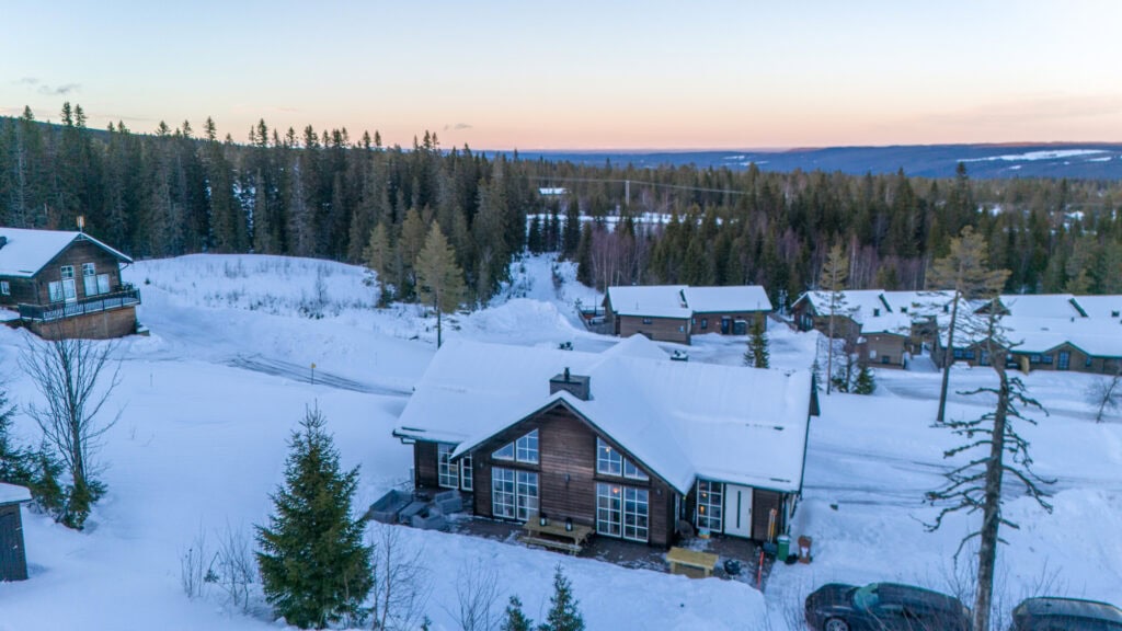 Salengodset i vinterlandskap med snötäckta hus och omgivande skog, perfekt för naturälskare och fritidsboende.
