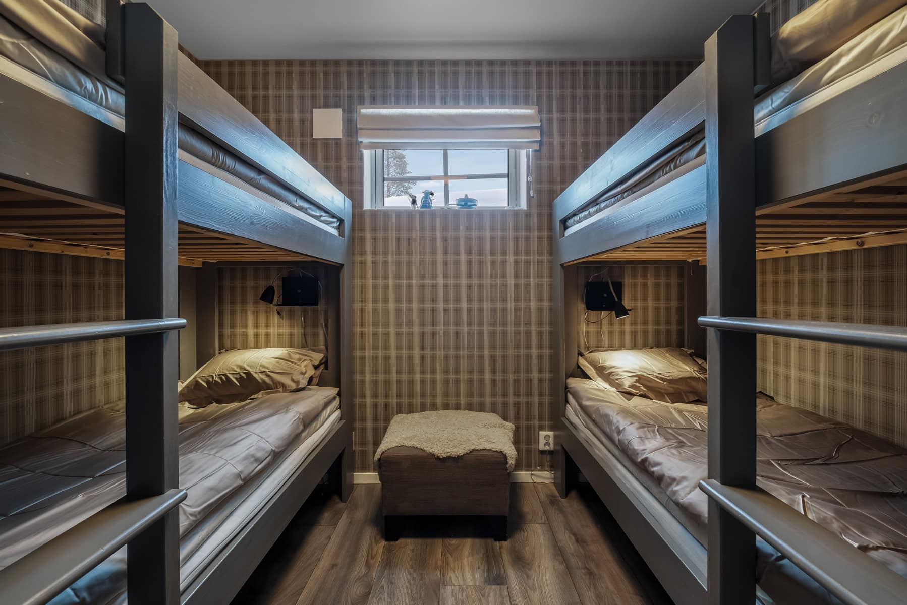 Klädda sovbunksrum med två våningssängar och mittpuff, mysig varm inredning, liten fönster med utsikt, perfekt för barn eller grupper, nära naturen.