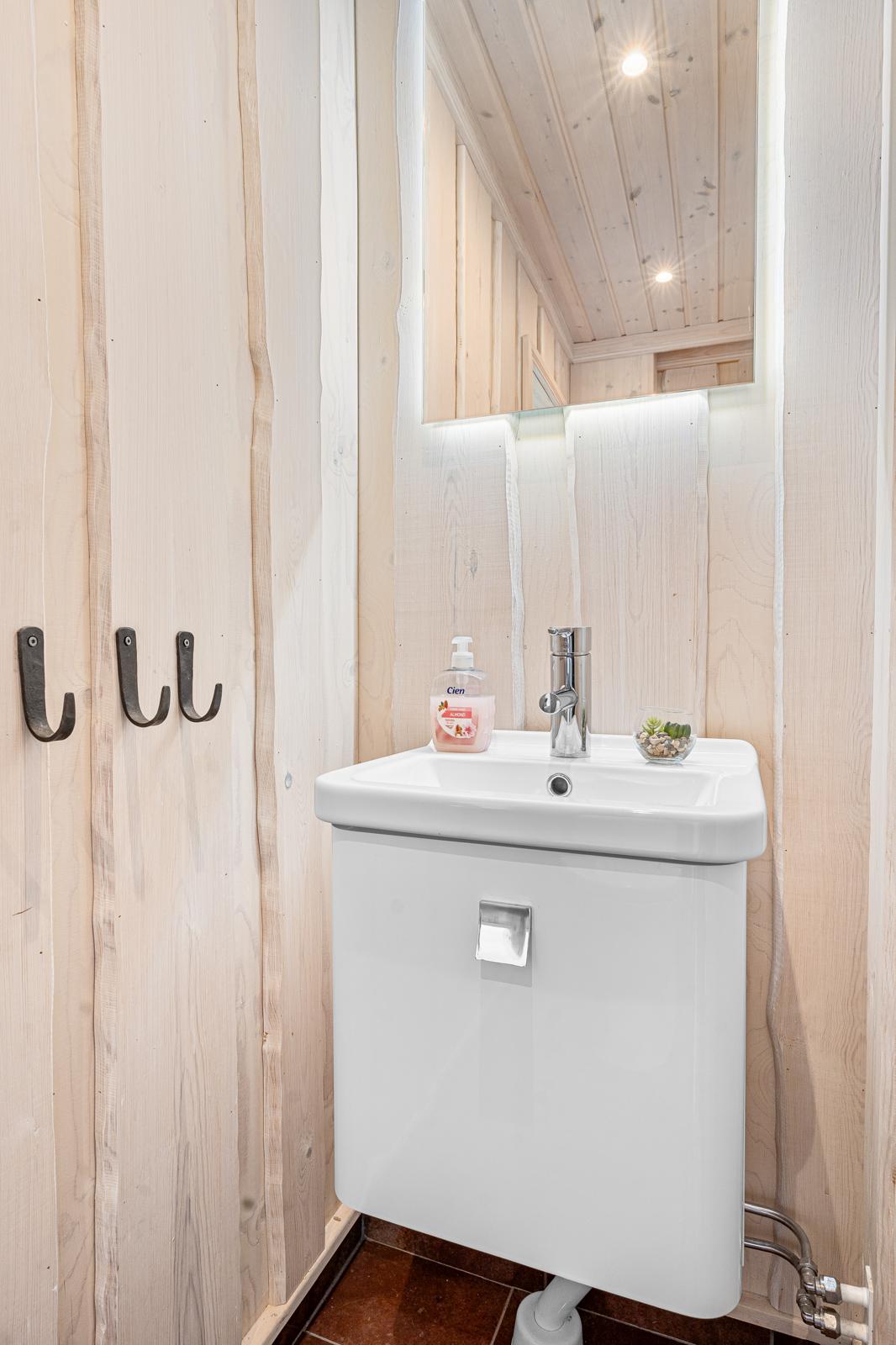 Litet badrum med träväggar och handfat.