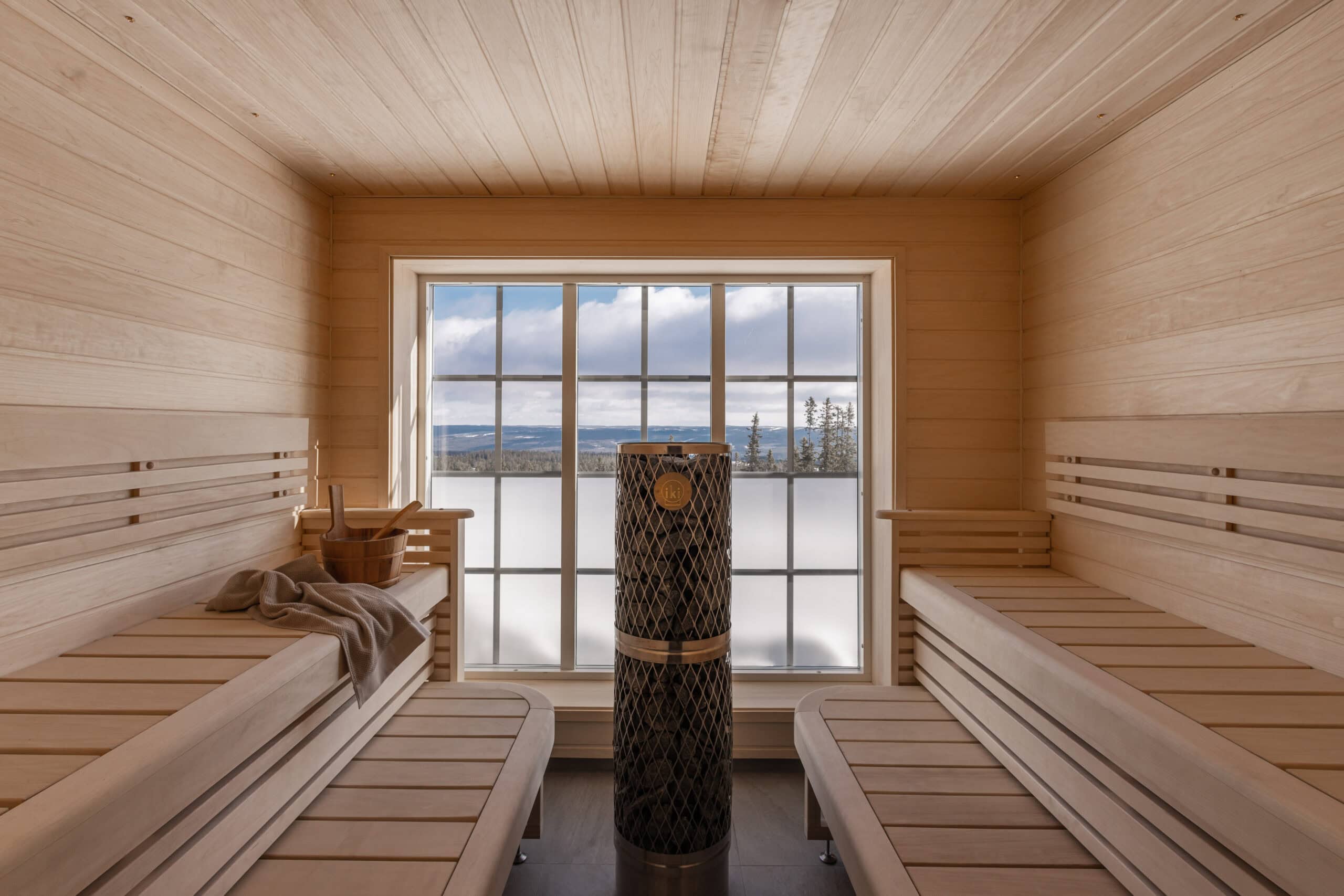 Wunderschöne Sauna im Innenbereich mit Holzwänden und Blick auf das Wasser durch große Fenster – ideal zum Entspannen und für das Wohlbefinden.