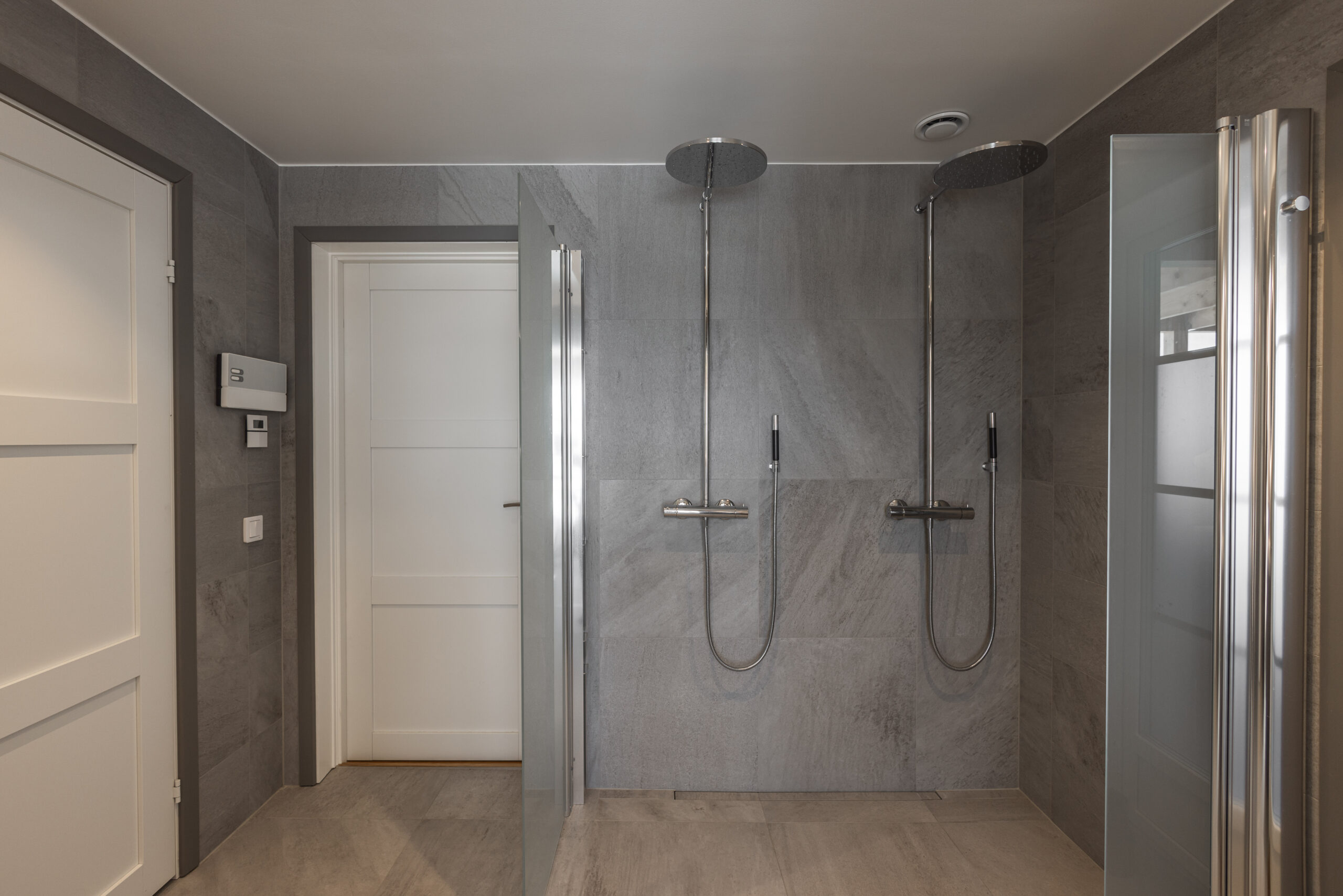Modern duschrum med dubbla duschar och minimalistisk design, perfekt för avkoppling och funktionalitet.