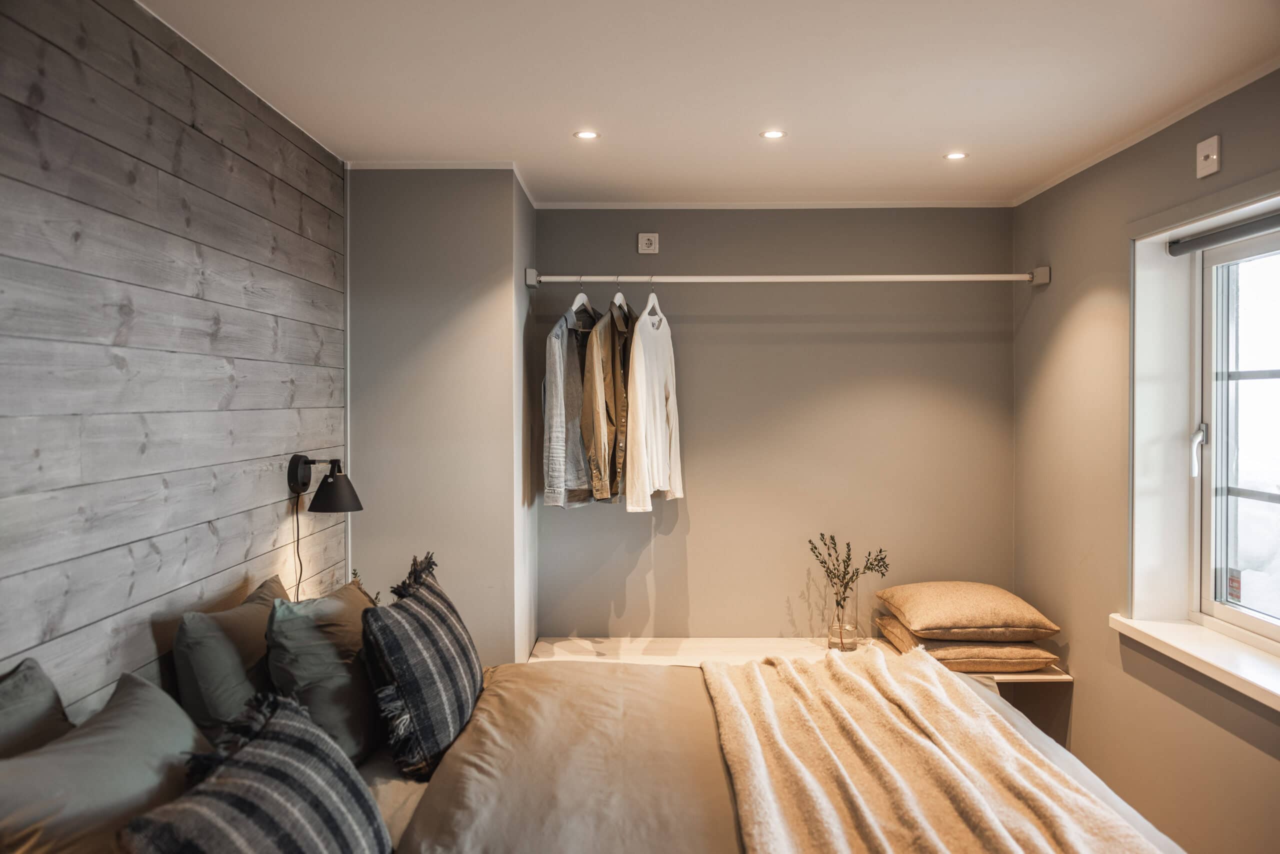 Modern bedroom with minimalist decor, neutral colors, and a cozy bed with multiple pillows, perfect for relaxation.