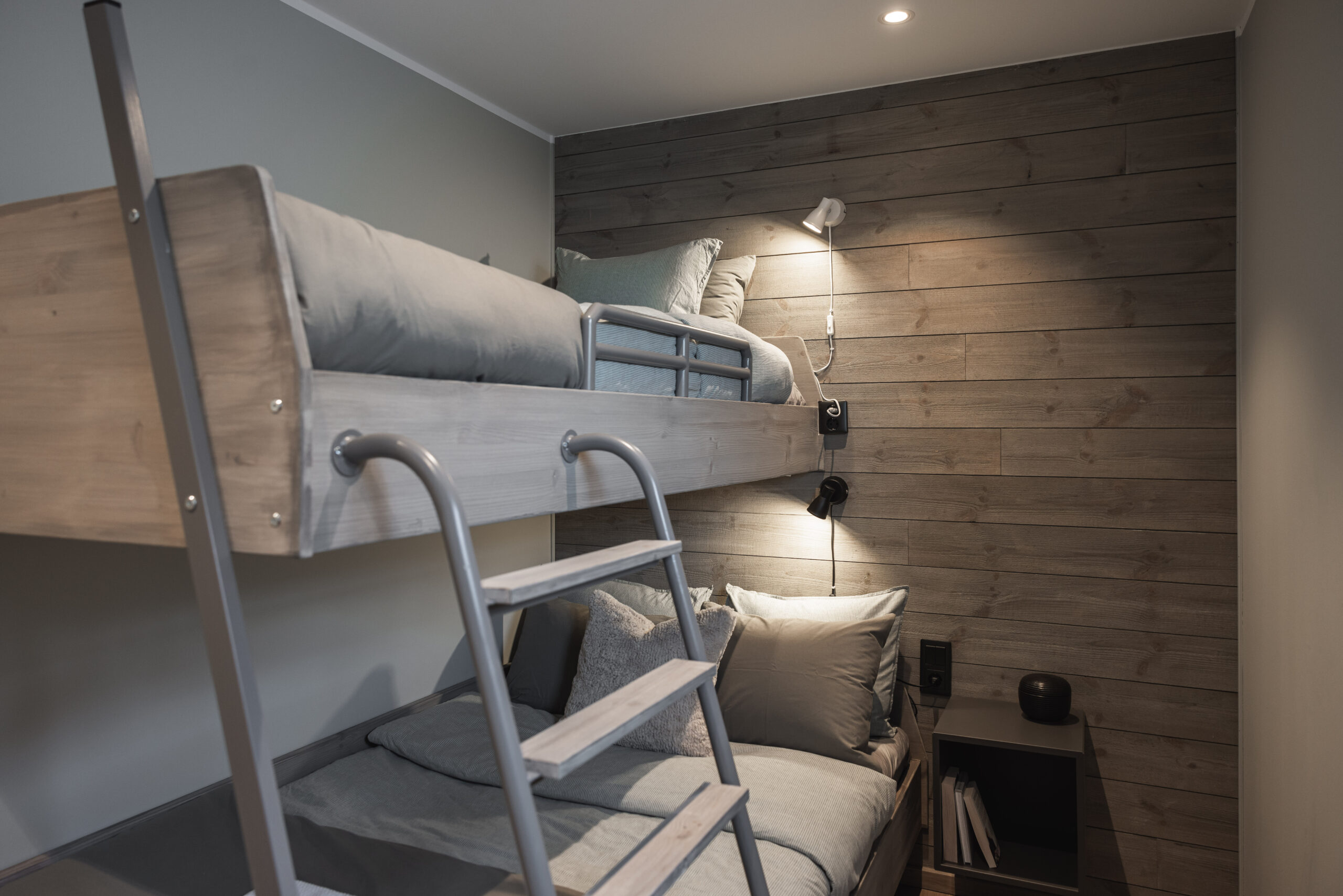 Sovrum med våningssäng, träväggar och modern belysning, perfekt för barn eller gäster.