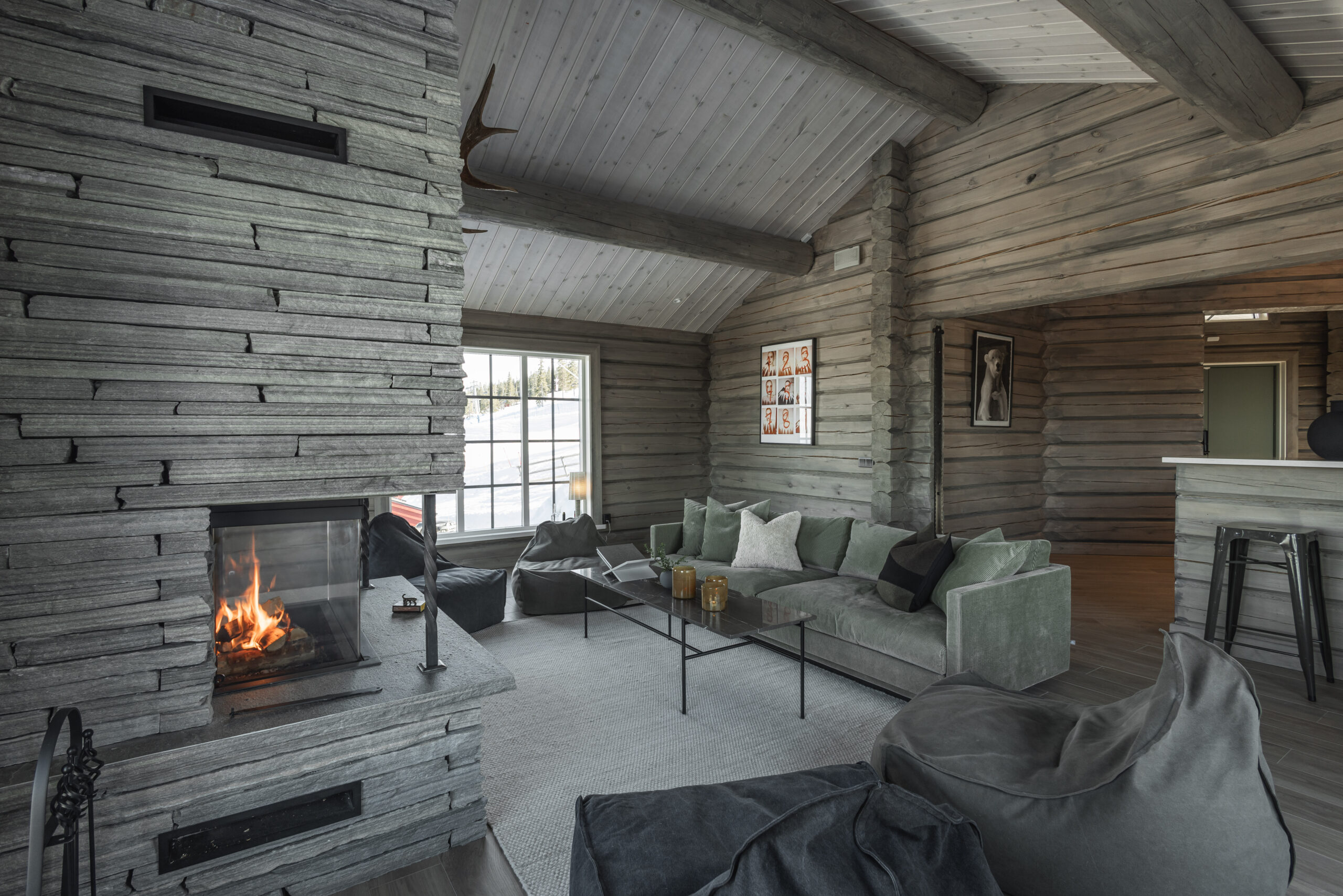 Wohnzimmer mit offenem Grundriss, großem Sofa, offenem Kamin und Holzwänden im salengodset-Stil.