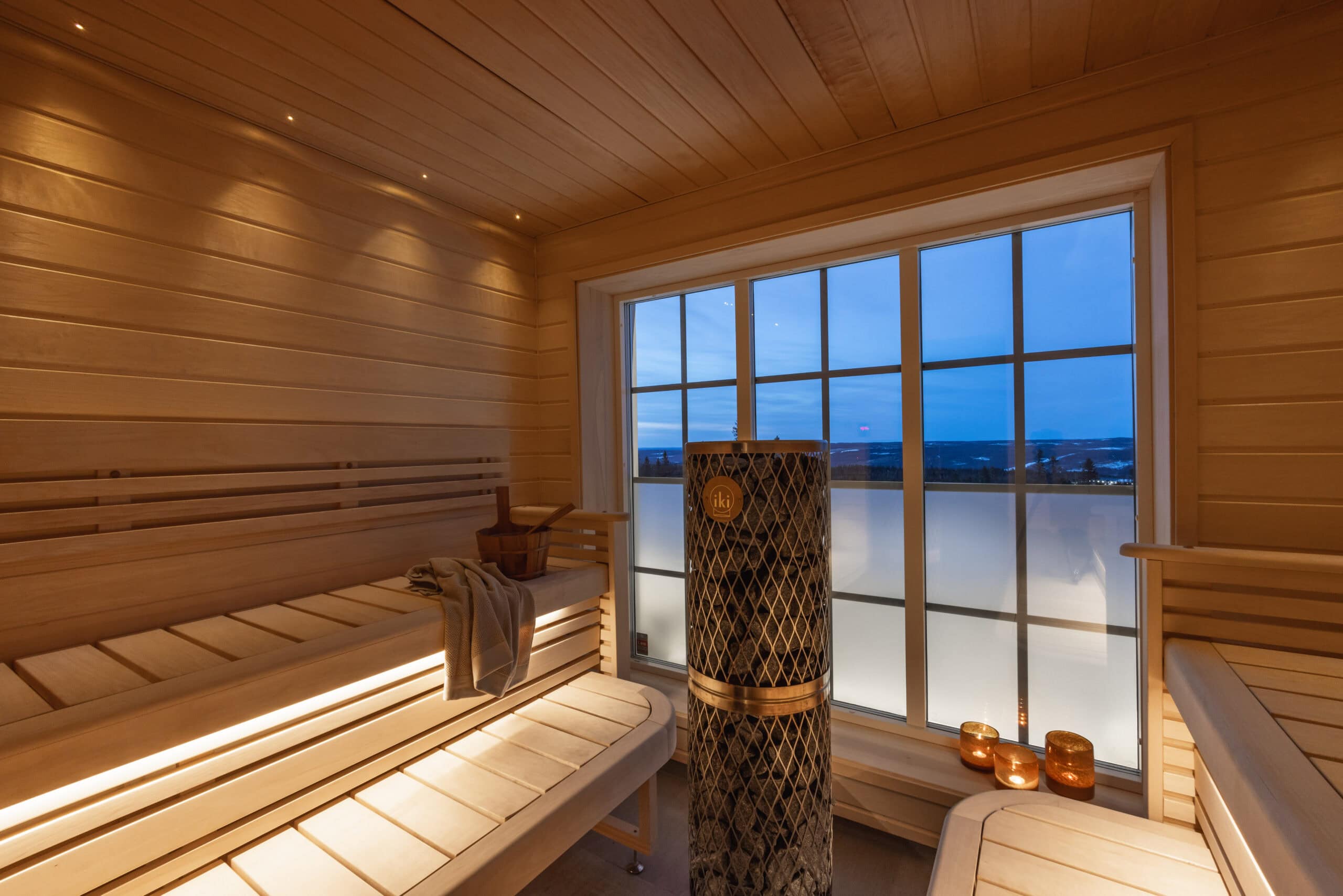 Vacker bastu inomhus med träpaneler, stora fönster och utsikt över landskapet, perfekt för avkoppling och wellness.