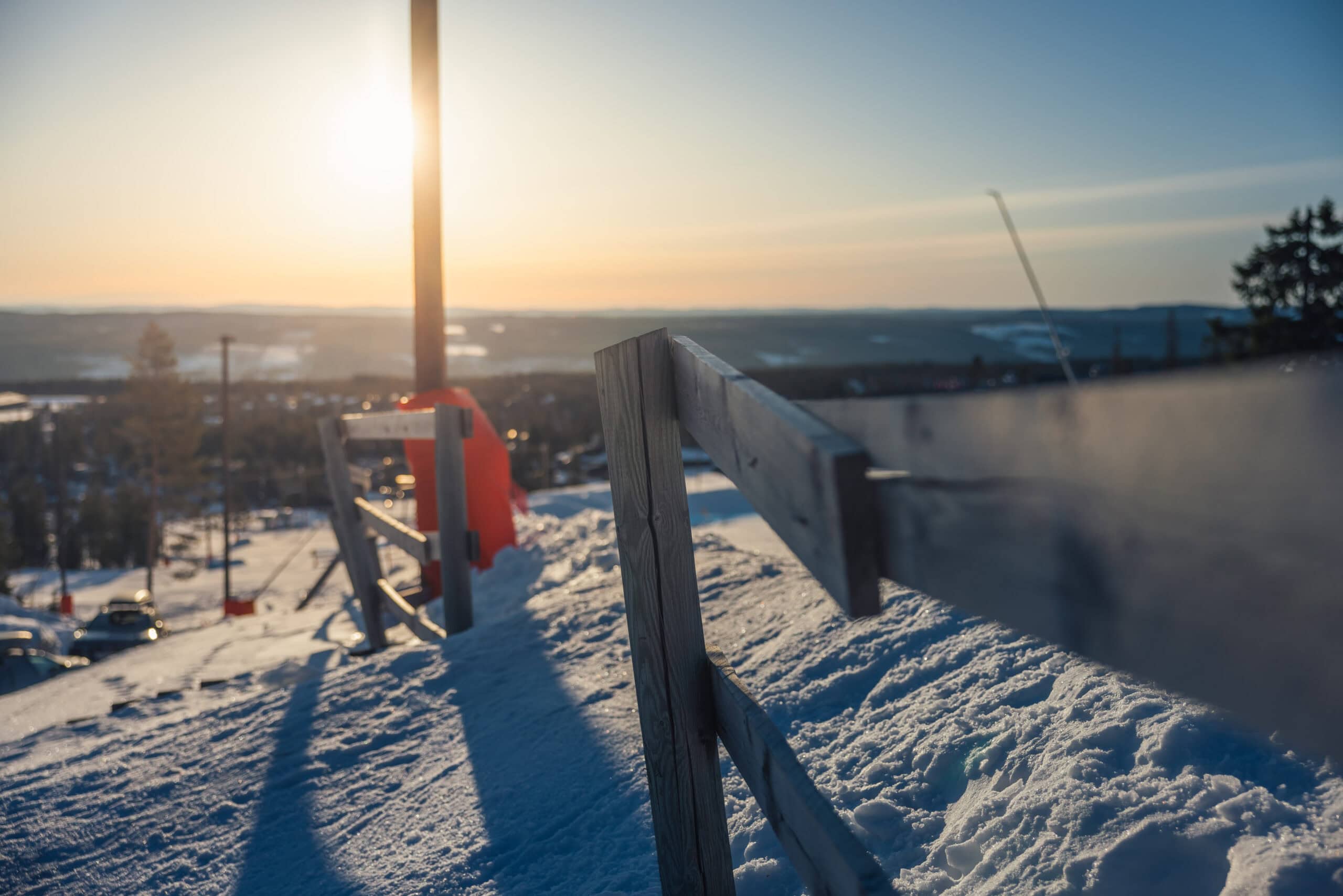 Vinterlandskap vid Salengodset med snö, trästaket och solnedgång i bakgrunden, skapar en lugn och naturskön atmosfär.