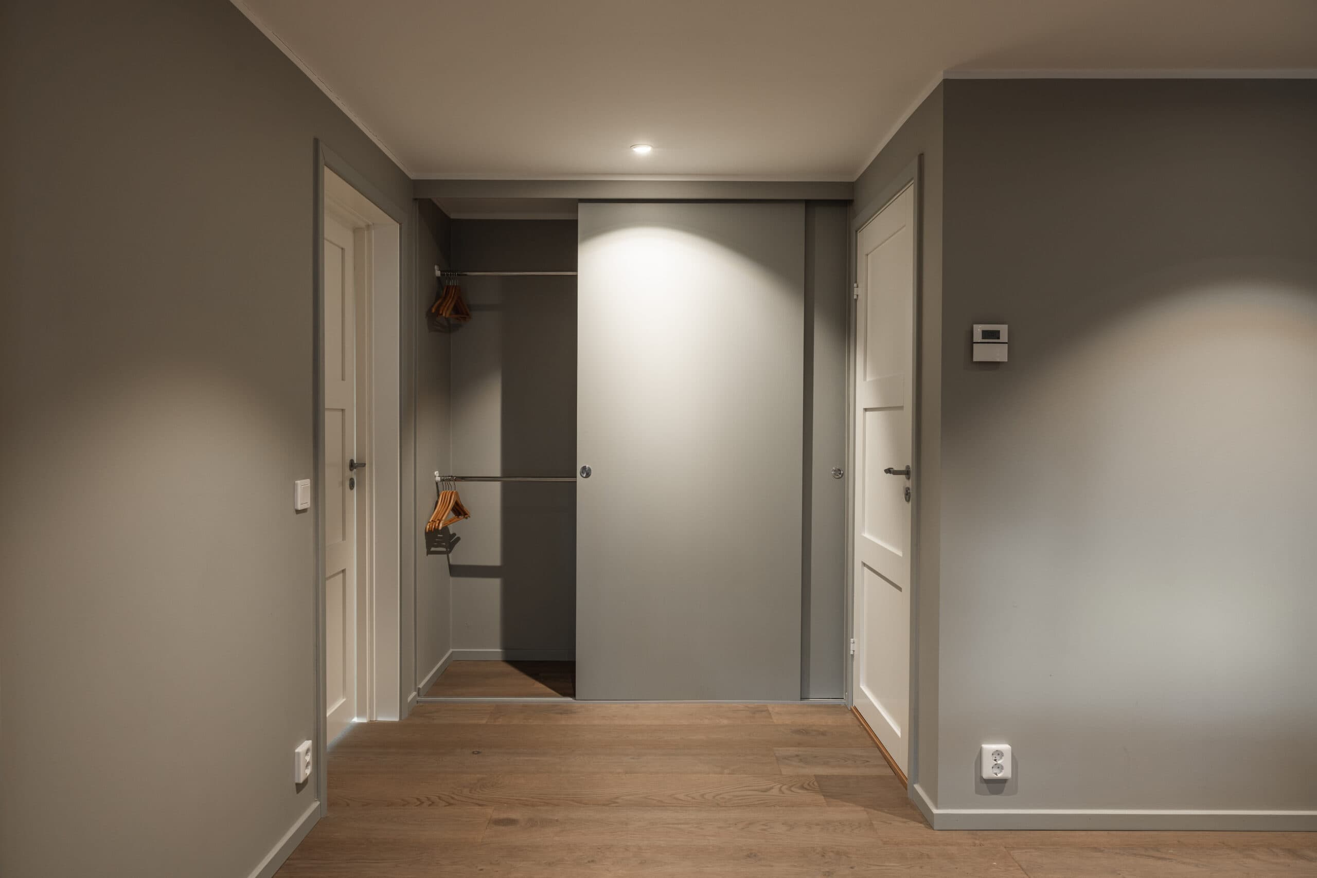 Modern inomhushall med grå väggar och trägolv, perfekt för heminredning och funktionell design.