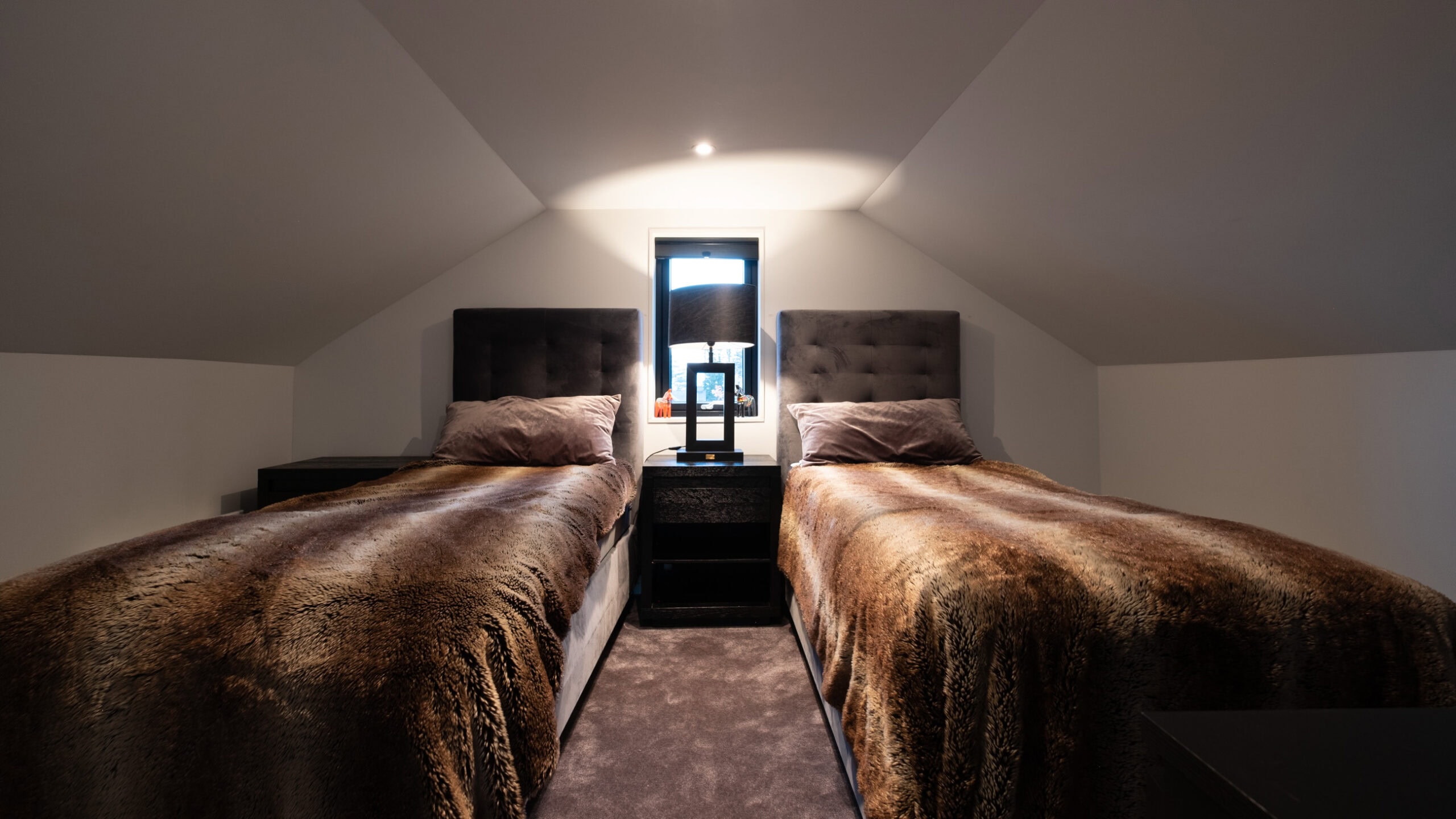 Two single beds with storage space beneath the sloping ceiling of the loft.