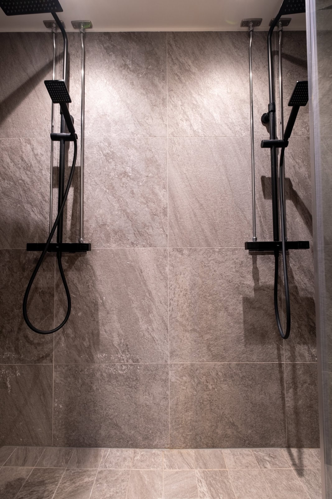 Shower room with two shower cubicles and grey stone walls.