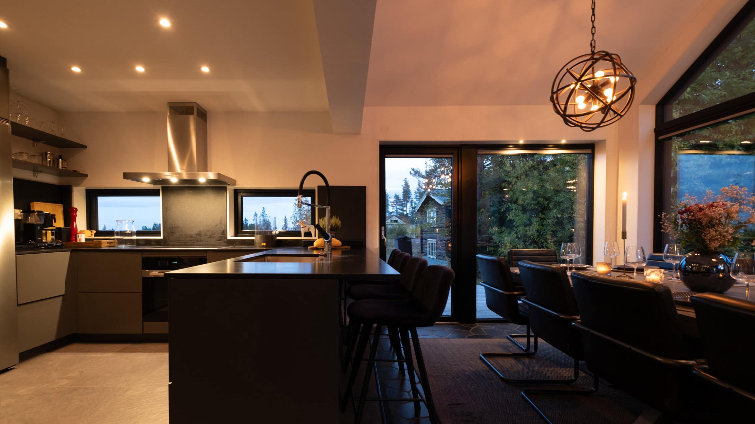 The kitchen and dining area in the evening light, with a kitchen island and an extractor fan above the hob.