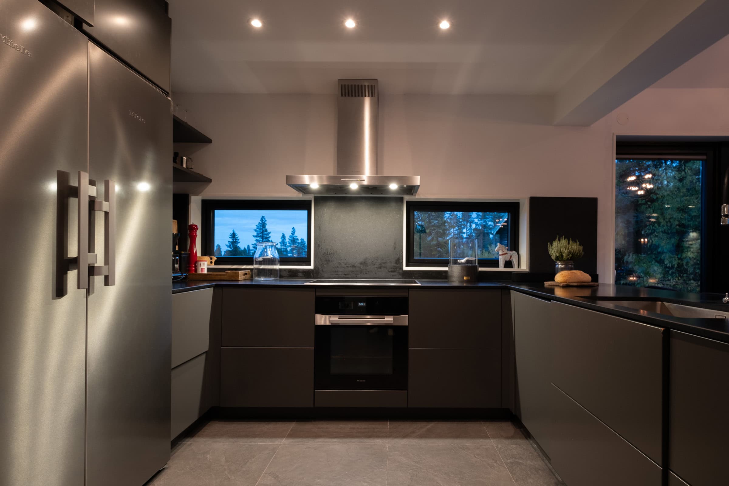 The kitchen, with dark cupboard doors, a built-in oven and a stainless-steel fridge-freezer.