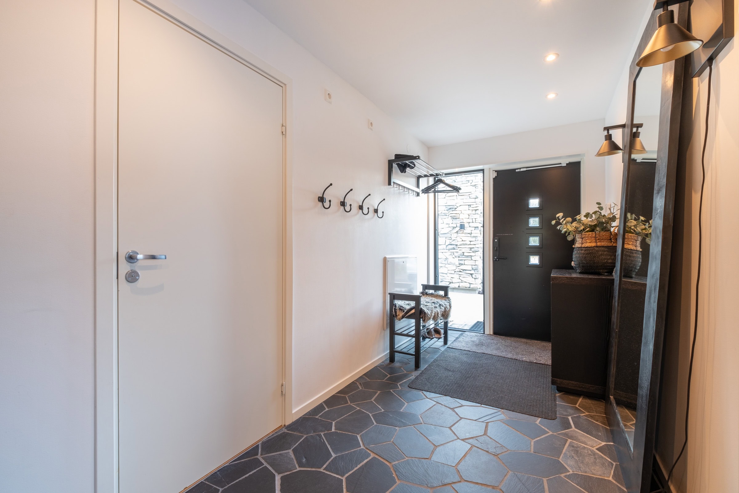 An entrance hall with a hexagonal tiled floor, coat hooks and light-coloured walls.