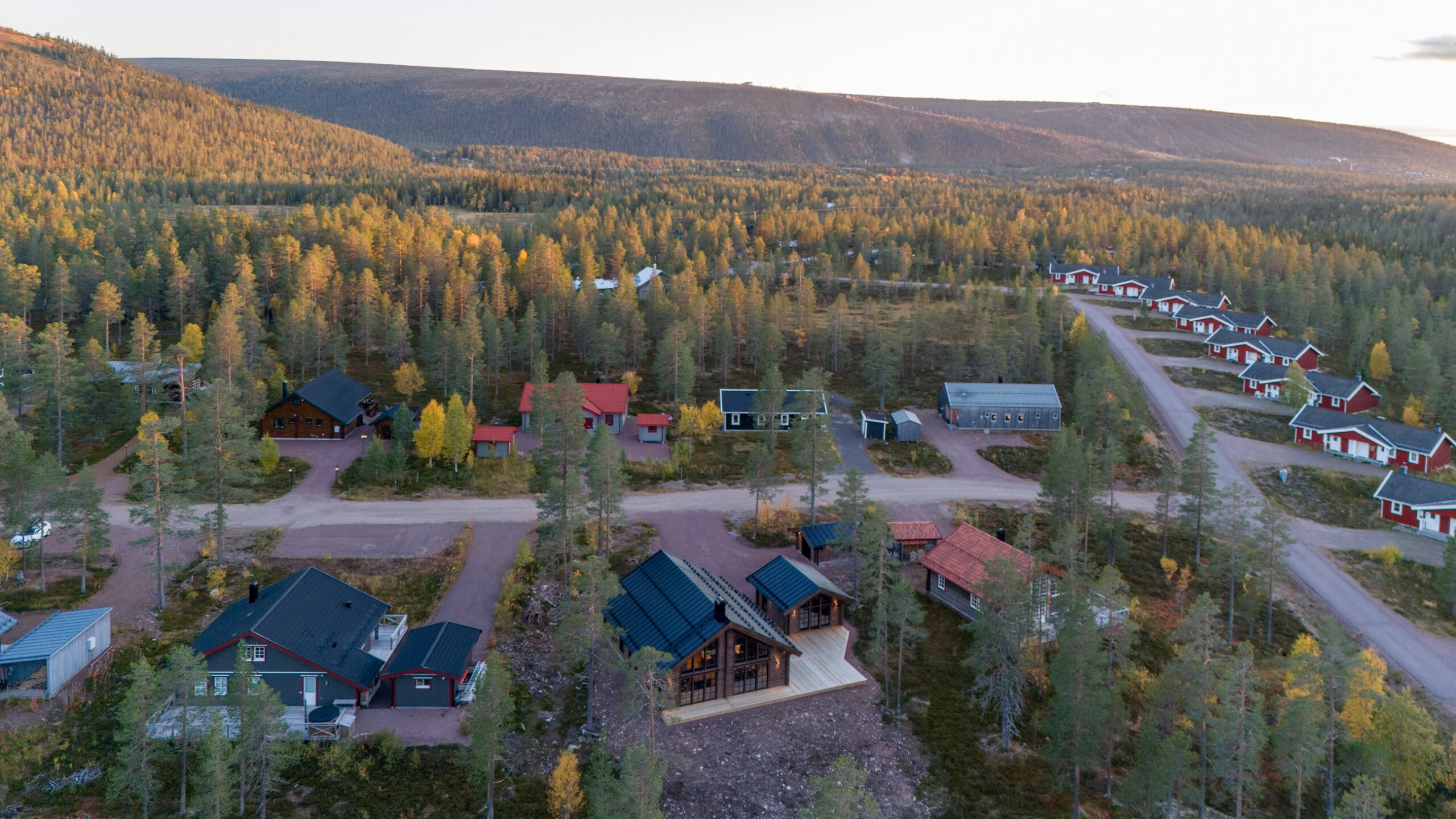 The holiday cottage area from the air, with the mountains and ski lifts in the background