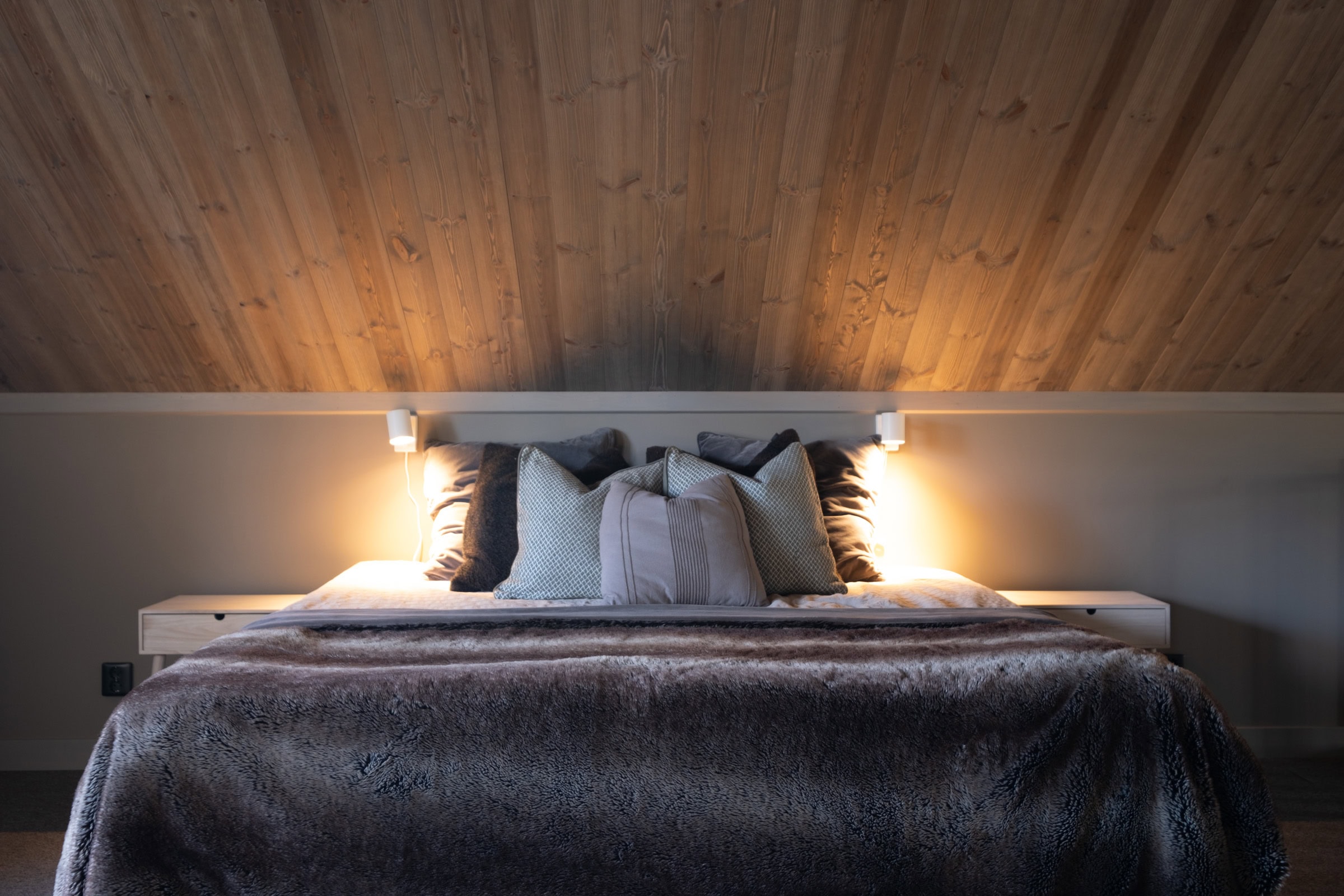 Bedroom with a double bed, a fold-down bed and light wooden panelling on the walls