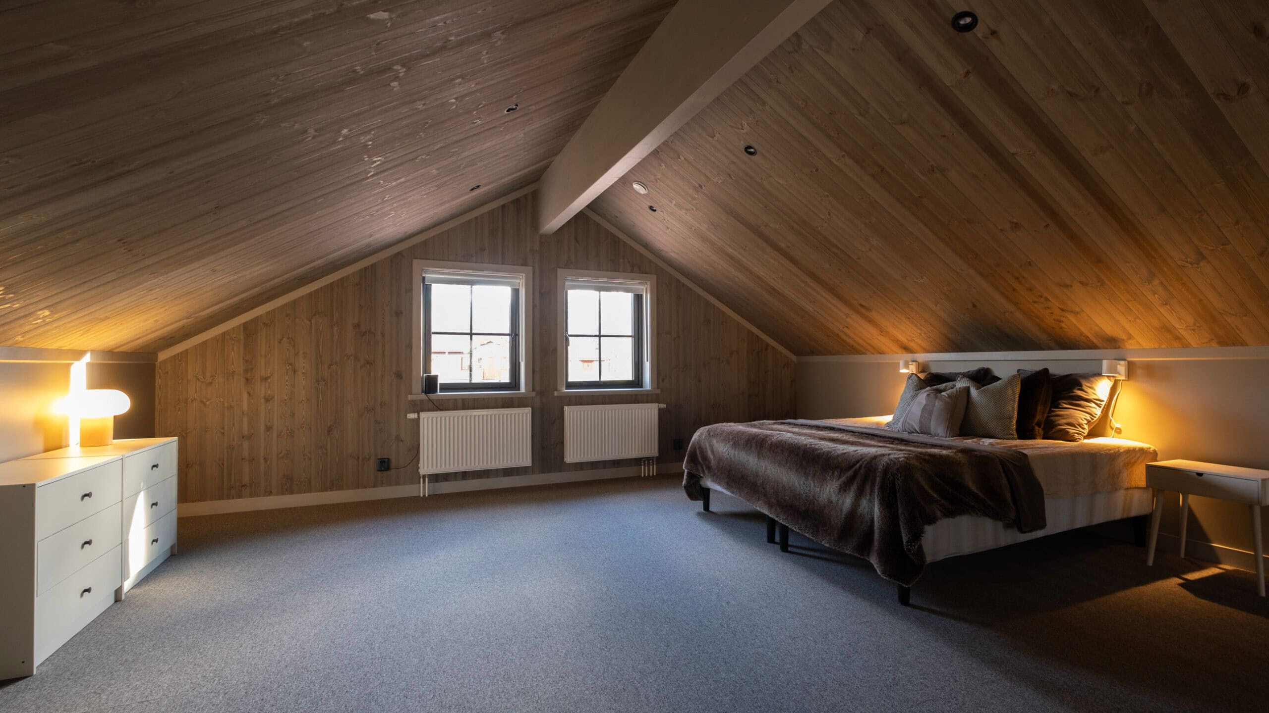 A sleeping area in the loft beneath the sloping roof, with a window in the gable end
