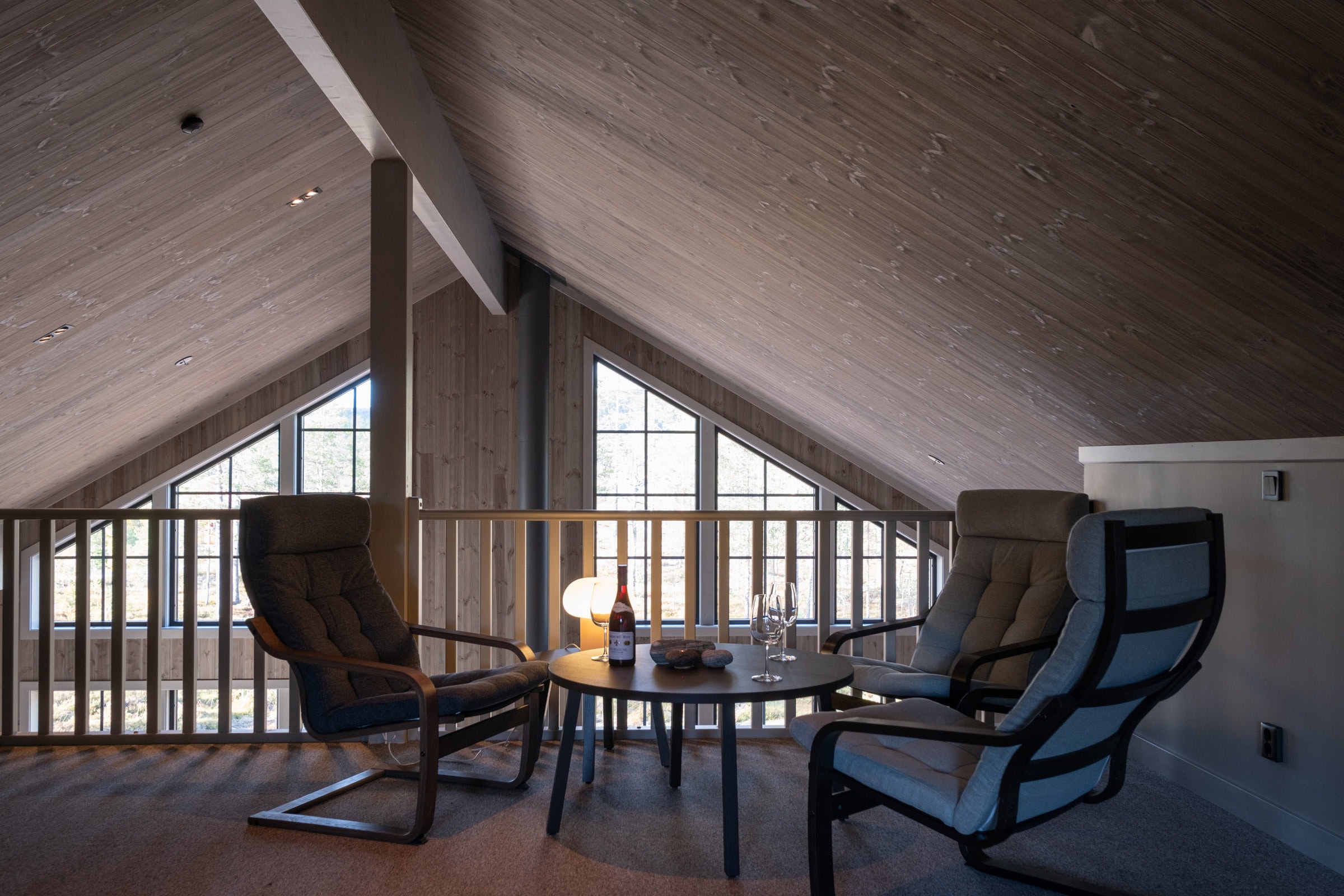 A seating area in the loft with armchairs and a railing facing the family room