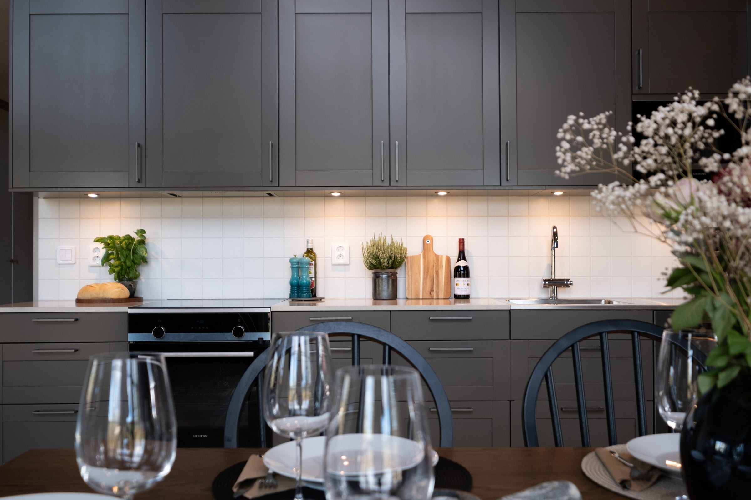 Kitchen worktop with an oven, wine glasses and fresh herbs