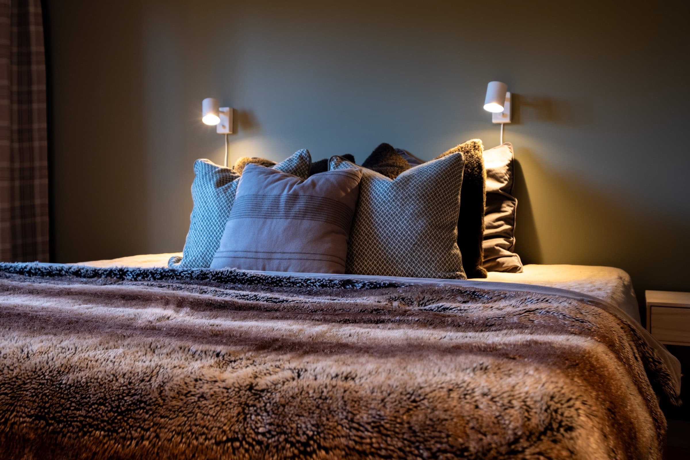 A made-up double bed with pillows and a blanket